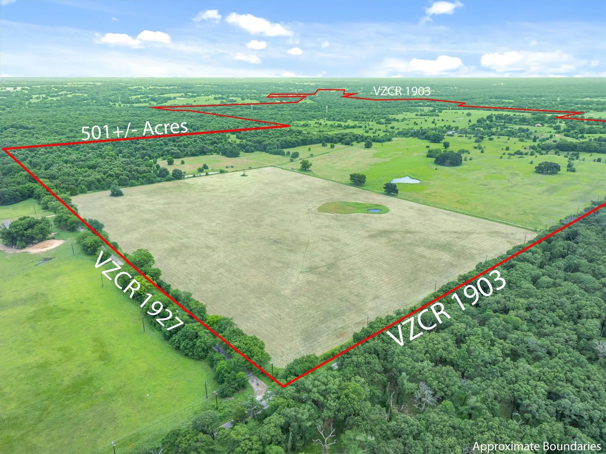 Extensive acreage featuring open fields, wooded areas, and a visible pond