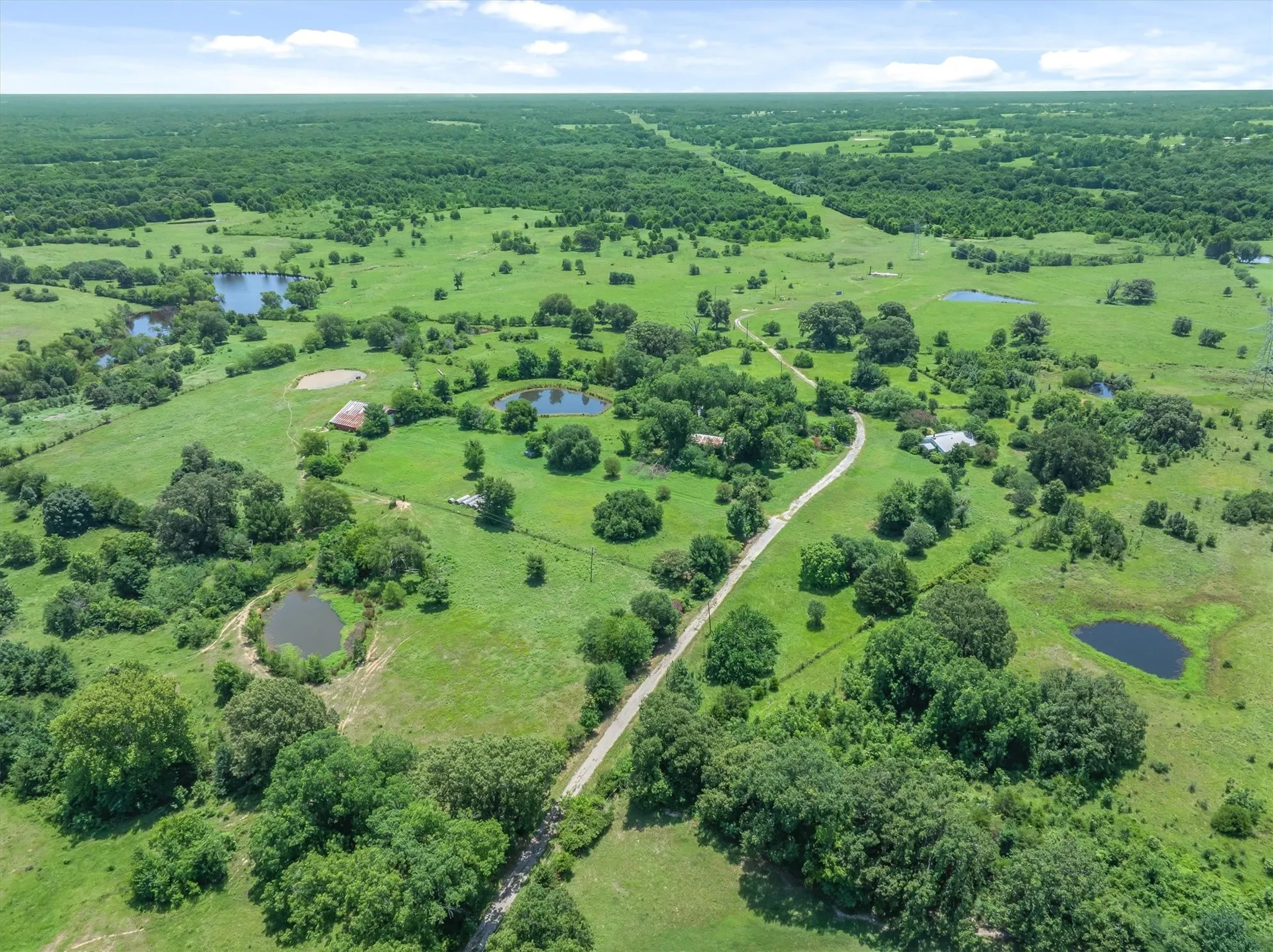 Expansive acreage featuring multiple ponds and a winding unpaved road