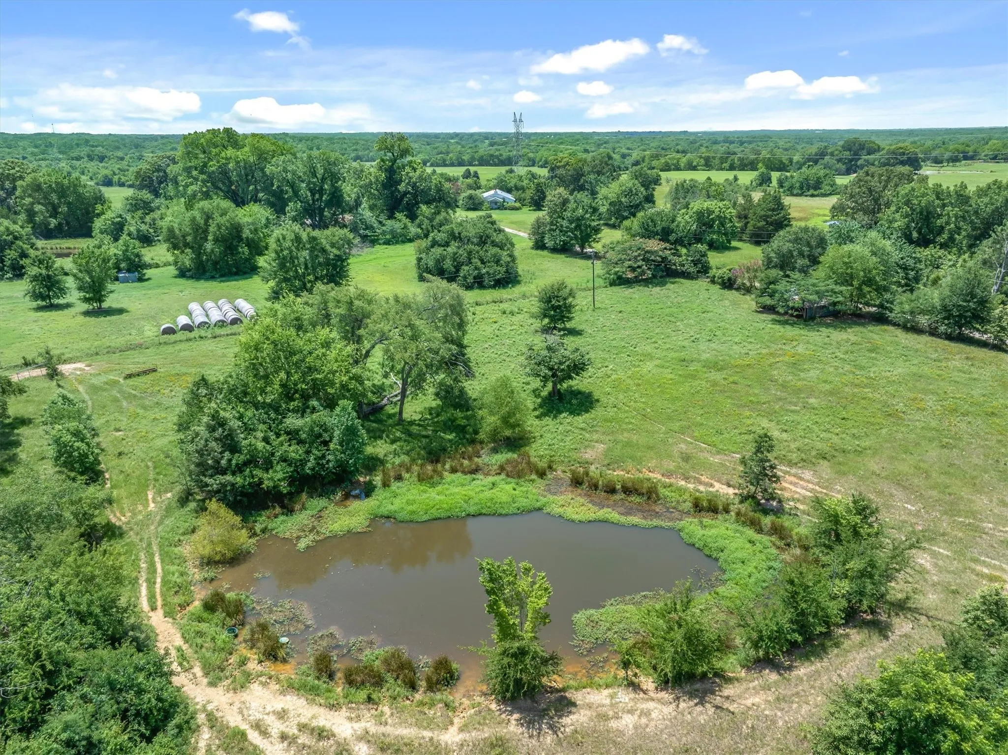 Natural pond with surrounding greenery and open fields