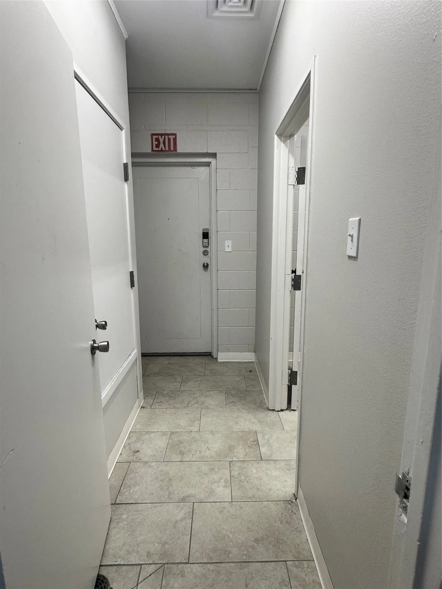 Hallway featuring tile flooring, painted walls, and multiple doorways