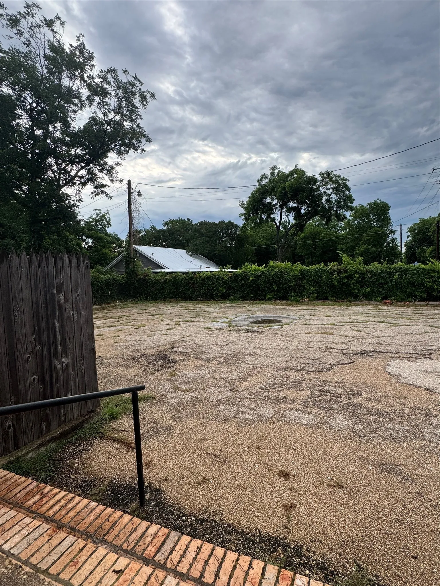 Expansive gravel lot featuring a brick retaining wall and black metal handrail