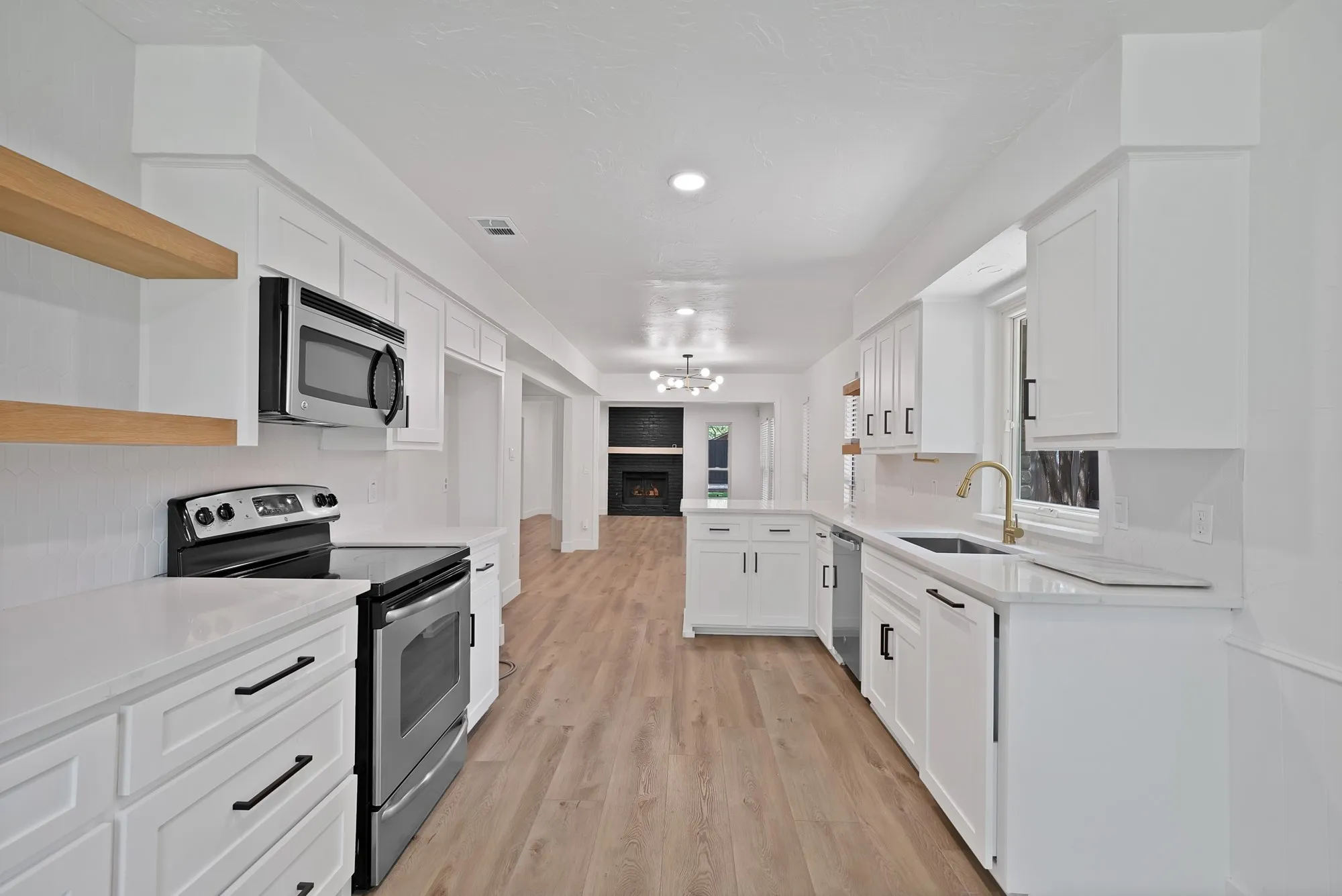 Contemporary kitchen featuring white shaker cabinetry, stainless steel appliances, light wood-finish flooring, and white countertops