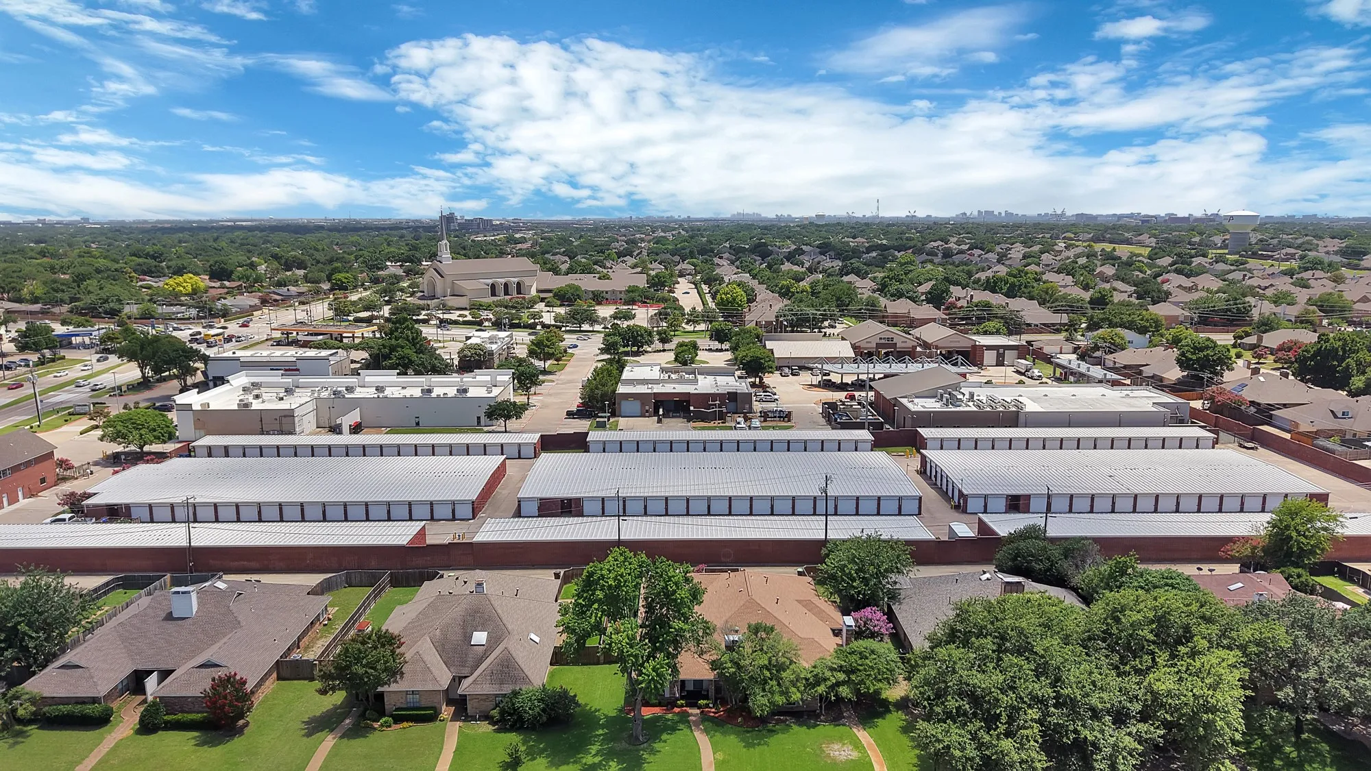 Aerial perspective showcasing a mixed-use neighborhood with residential properties, commercial structures, and multiple storage facilities