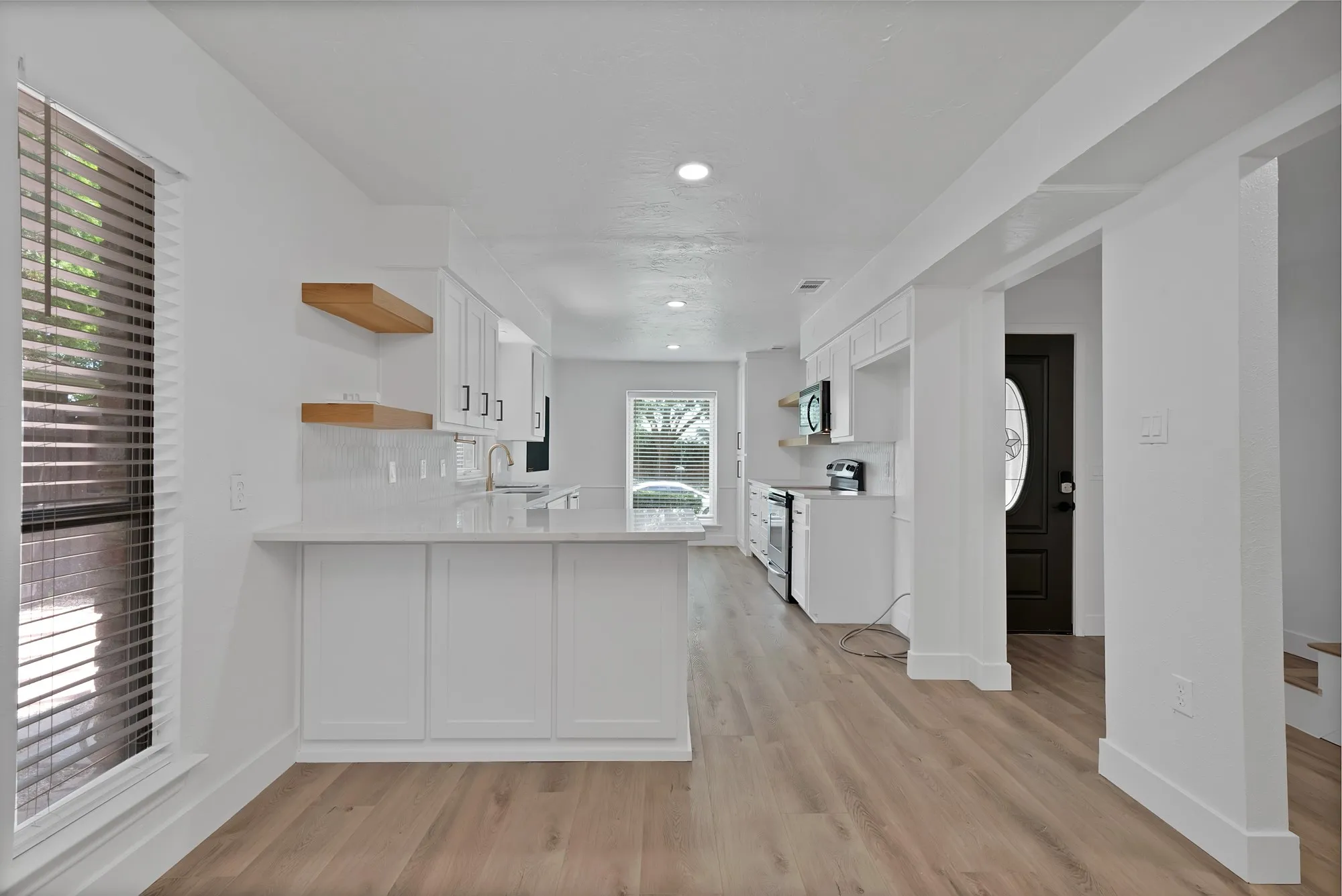 Modern kitchen with white cabinetry and light-tone wood-finish flooring