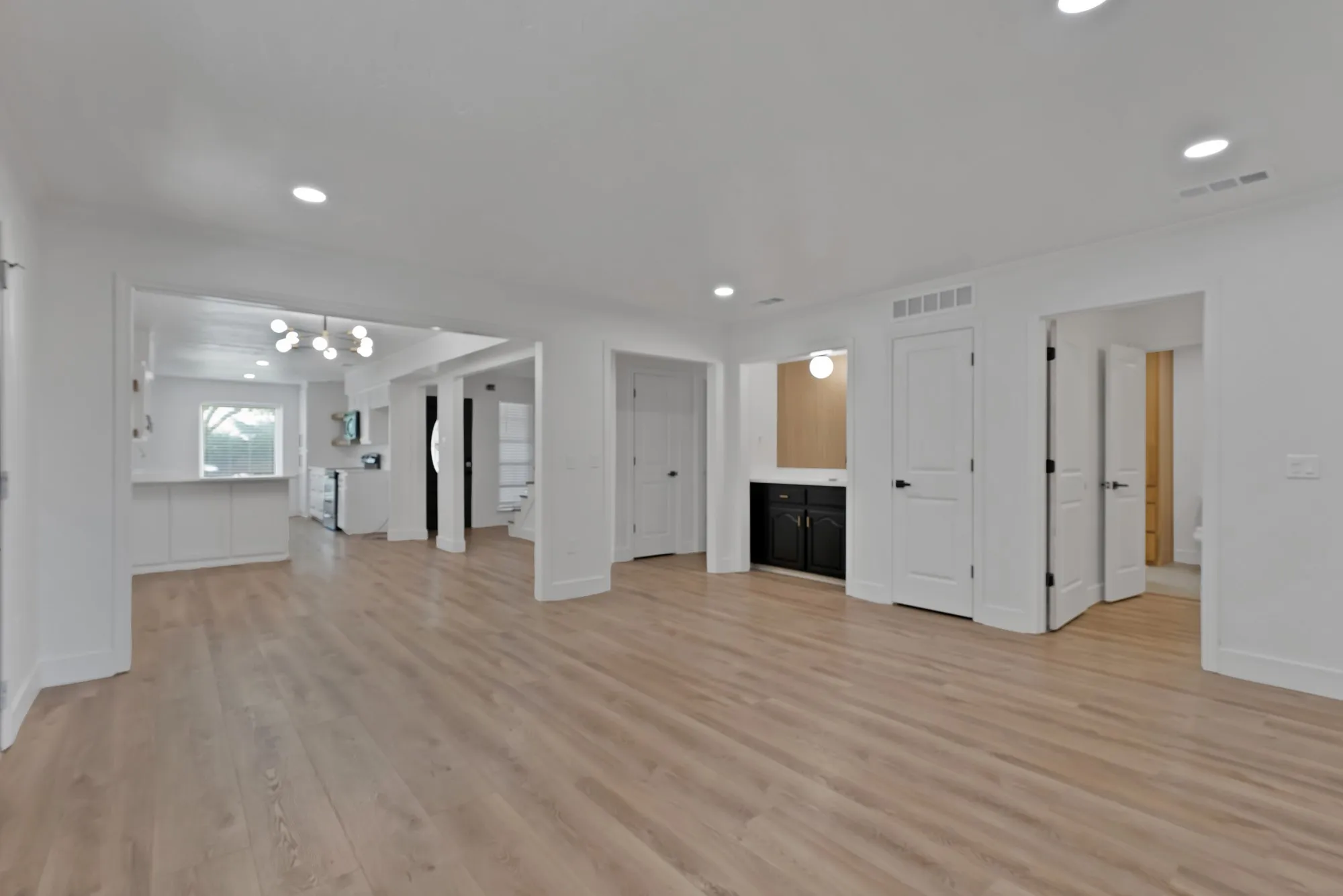 Spacious room featuring wood-finish flooring, recessed lighting, and a modern chandelier