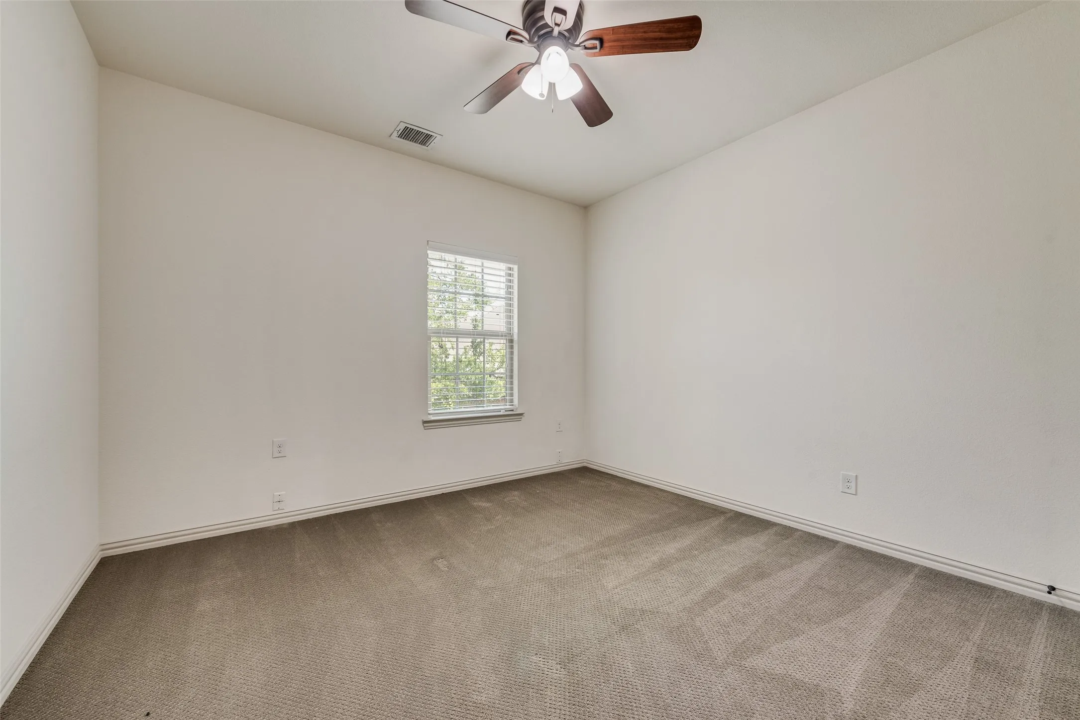 Carpeted room featuring a ceiling fan with integrated lighting, a single window with blinds, and white painted walls