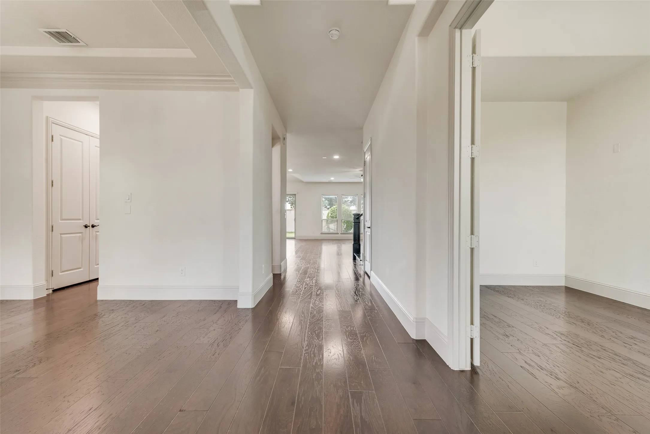 Hallway featuring wood-finish flooring, white walls, and recessed lighting