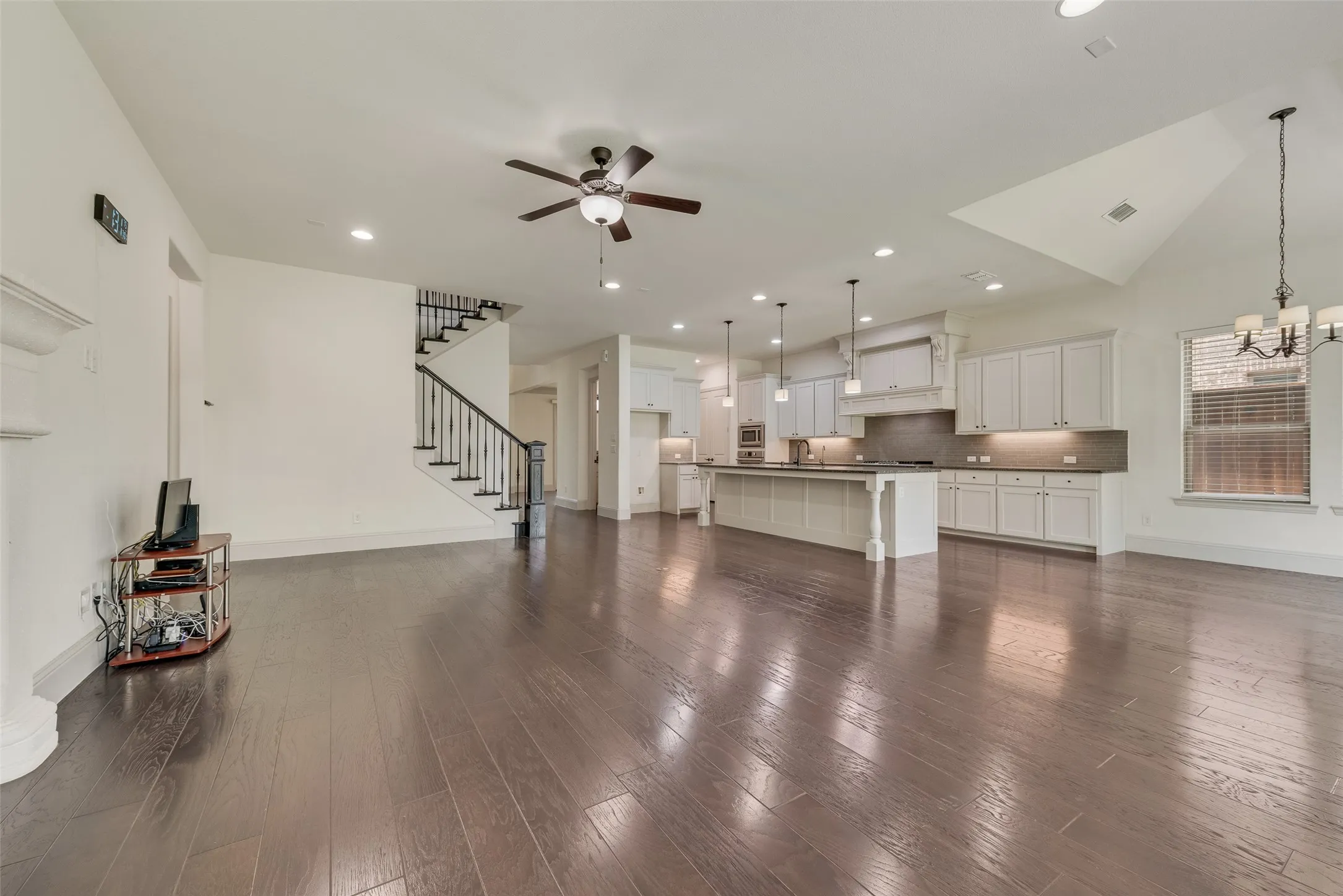 Spacious open-concept living area featuring wood-finish flooring, a vaulted ceiling, and a ceiling fan
