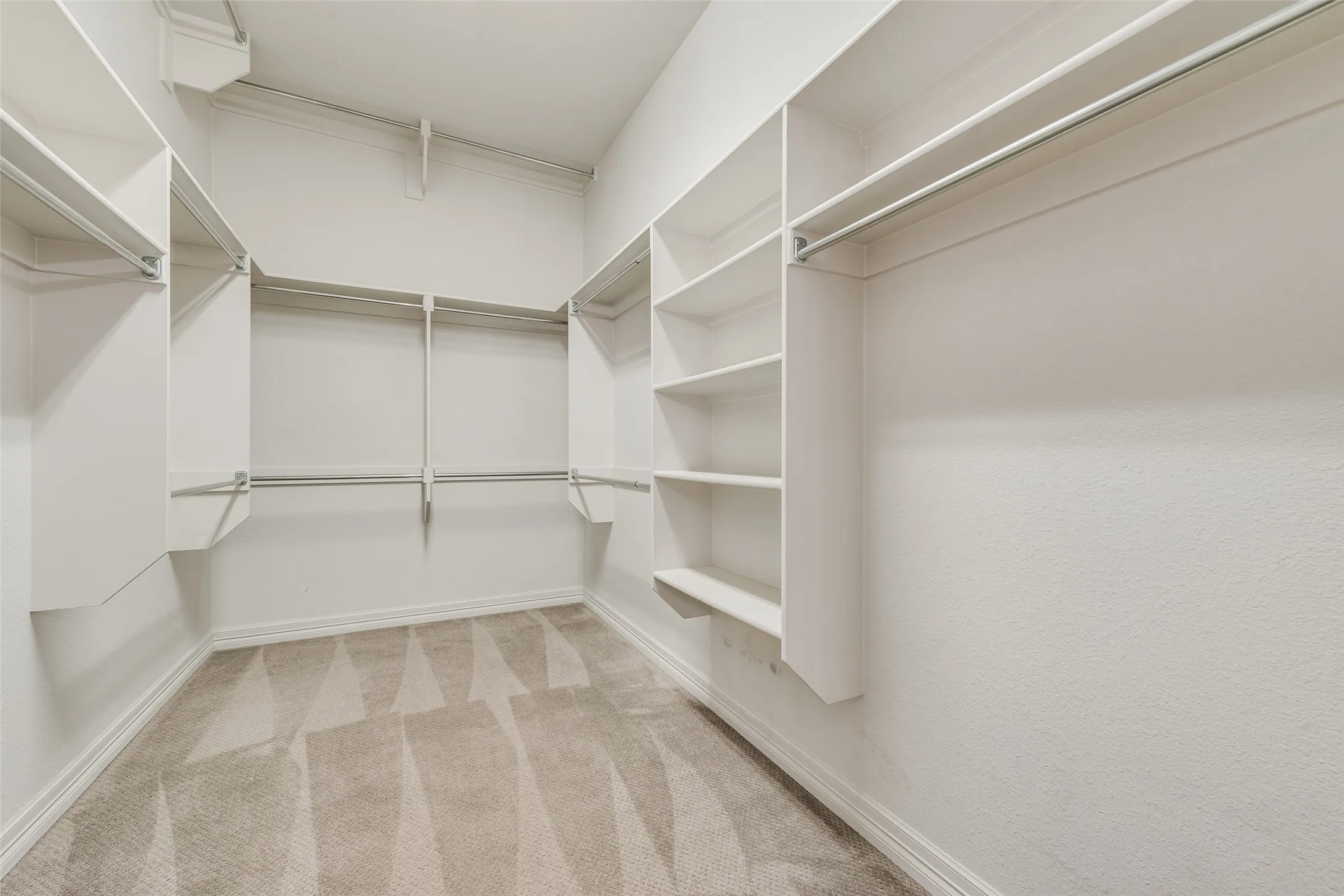 Walk-in closet featuring built-in shelving, multiple hanging rods, baseboards, and carpet flooring