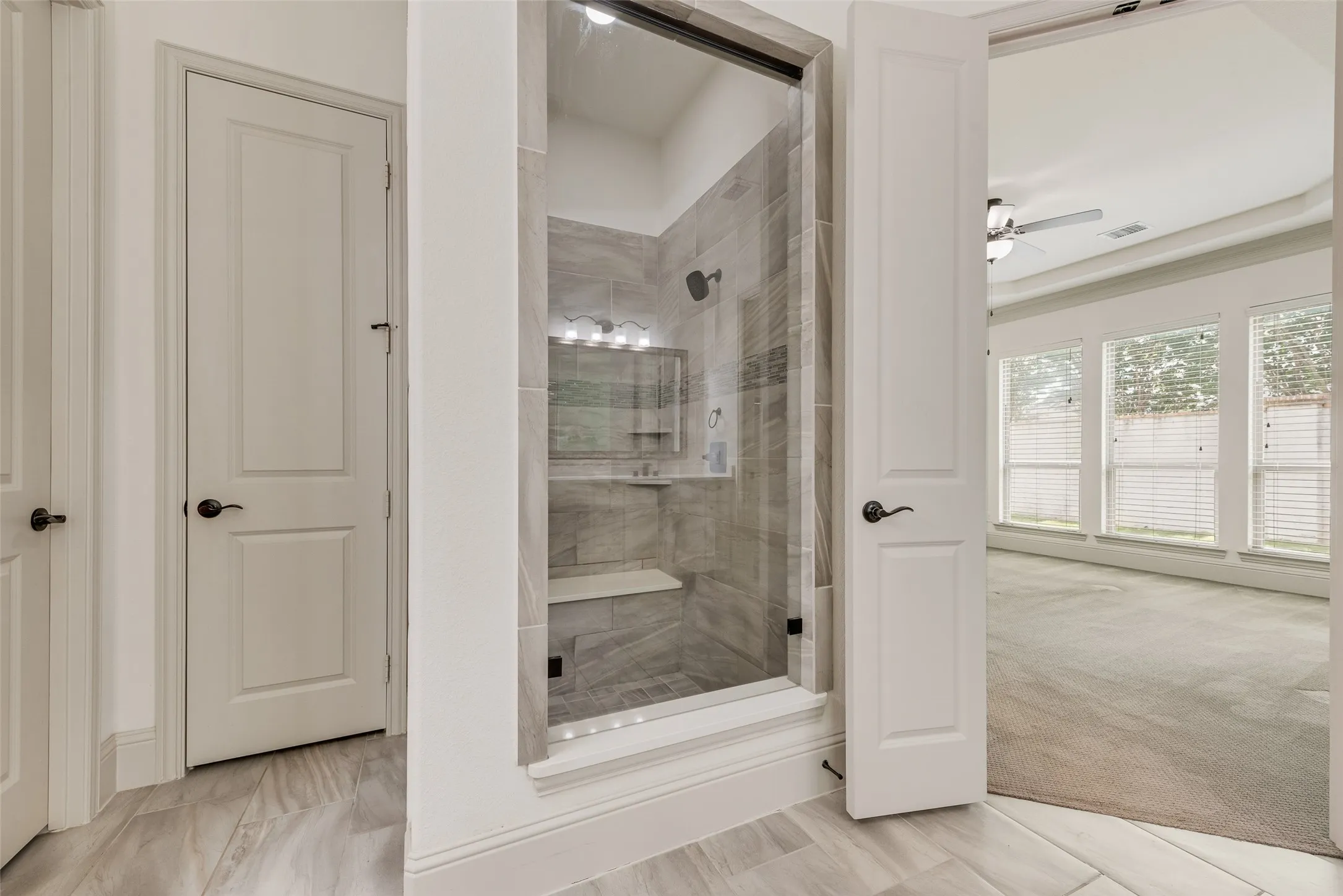 Contemporary glass-enclosed shower with a built-in bench and tiled walls