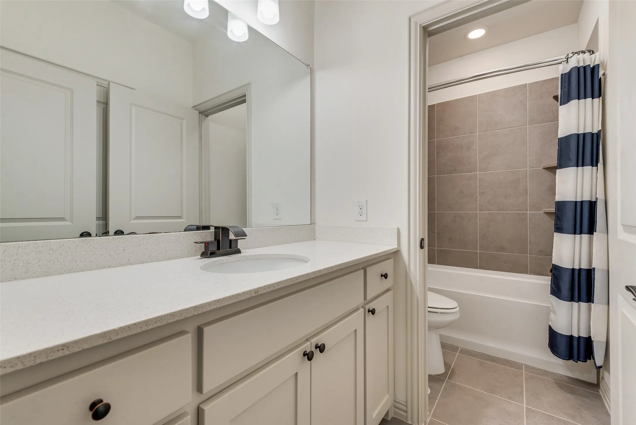 Bathroom vanity featuring a light-colored countertop, undermount sink, and matte black faucet