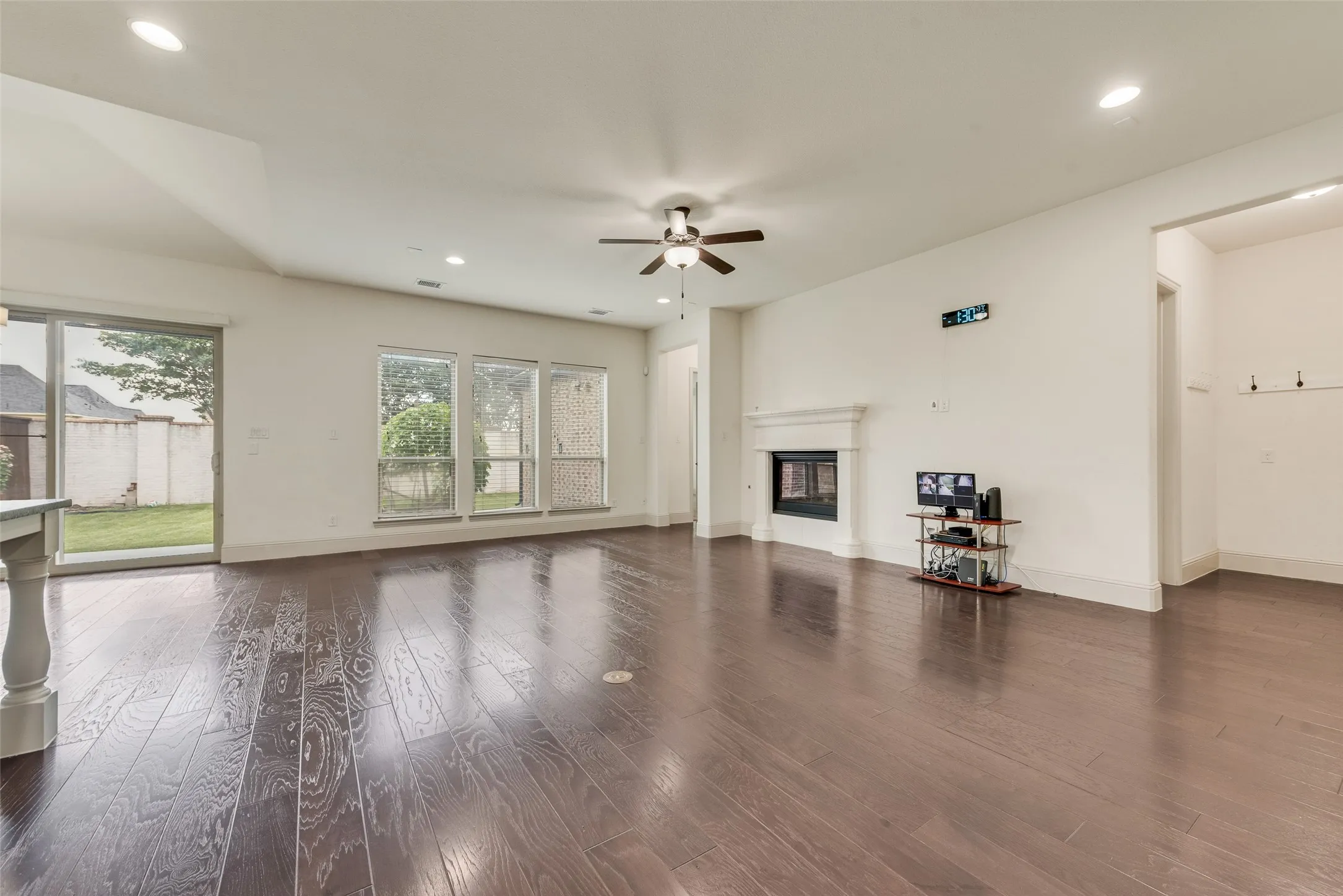 Spacious living area featuring rich wood-finish flooring, a contemporary fireplace with a classic mantel, and multiple windows providing abundant natural light