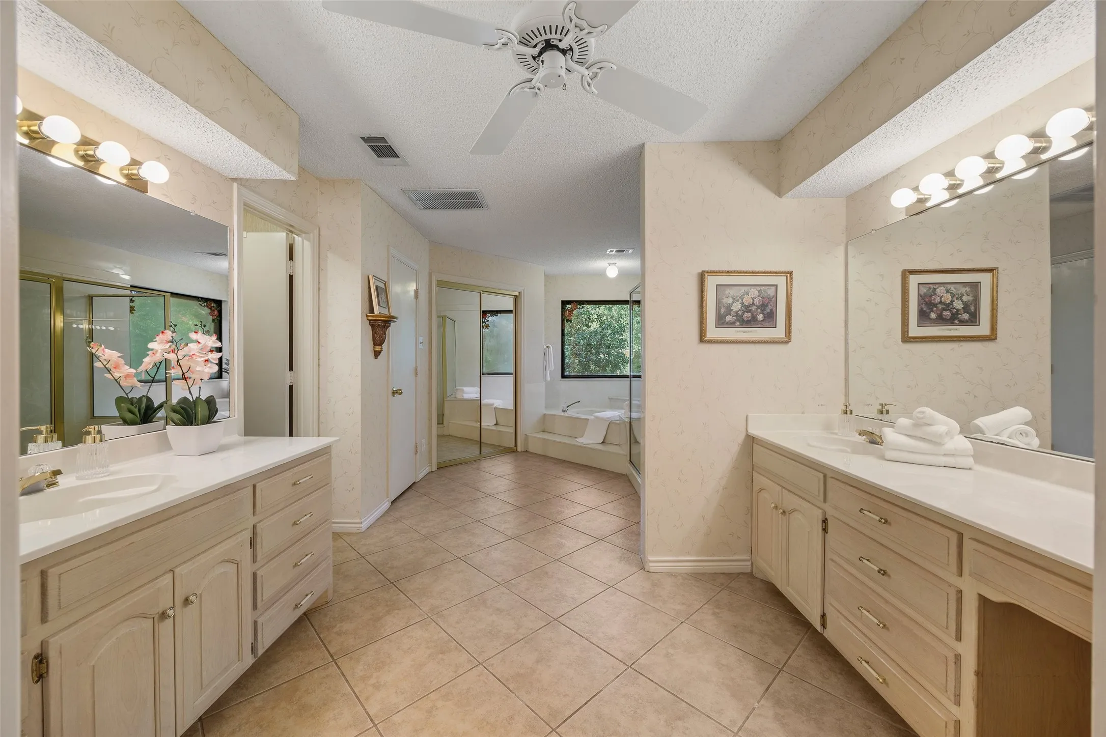 Spacious bathroom featuring dual vanities with integrated sinks, ample counter space, and extensive cabinetry