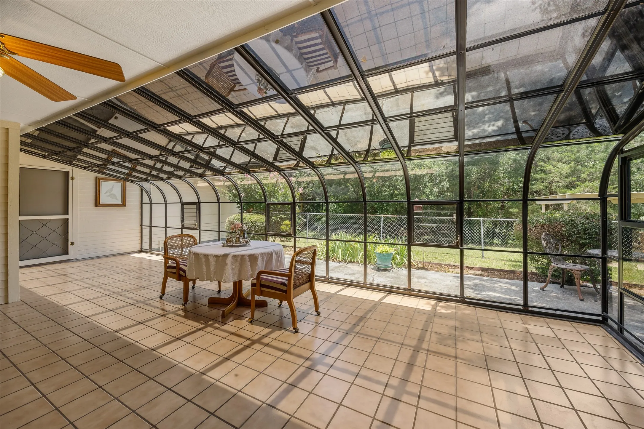 Expansive sunroom featuring a vaulted glass ceiling, full-height glass walls, and light-toned tile flooring