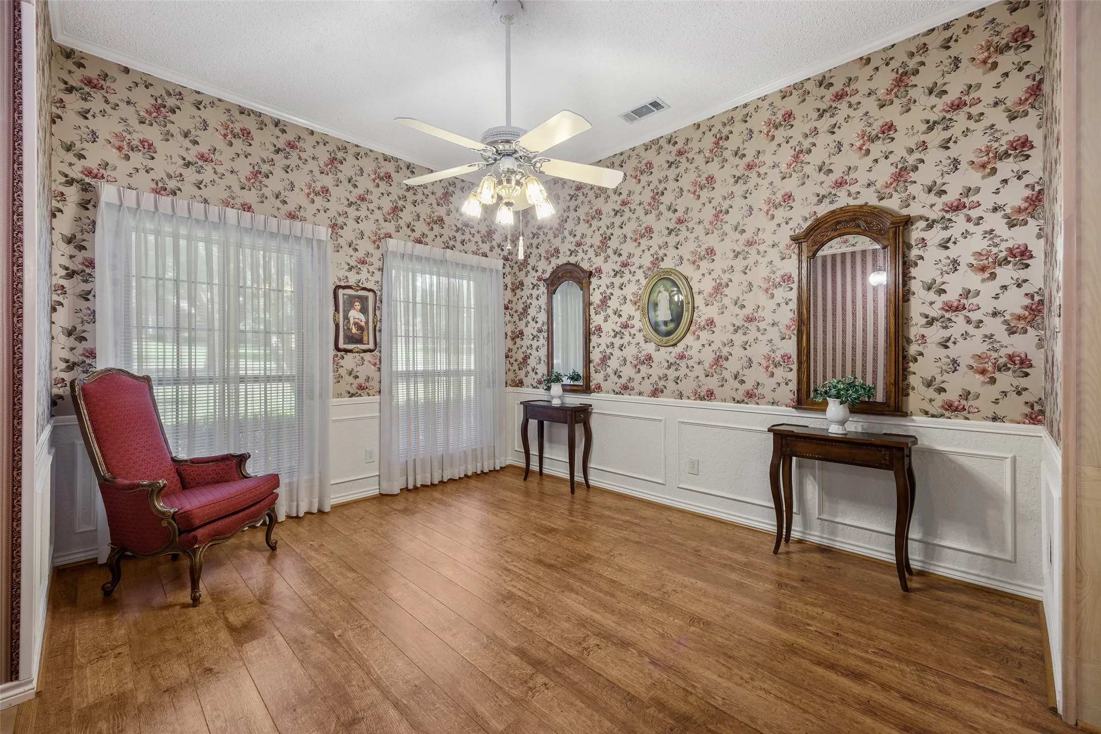 Spacious room featuring wood-finish flooring, floral wallpaper, and wainscoting