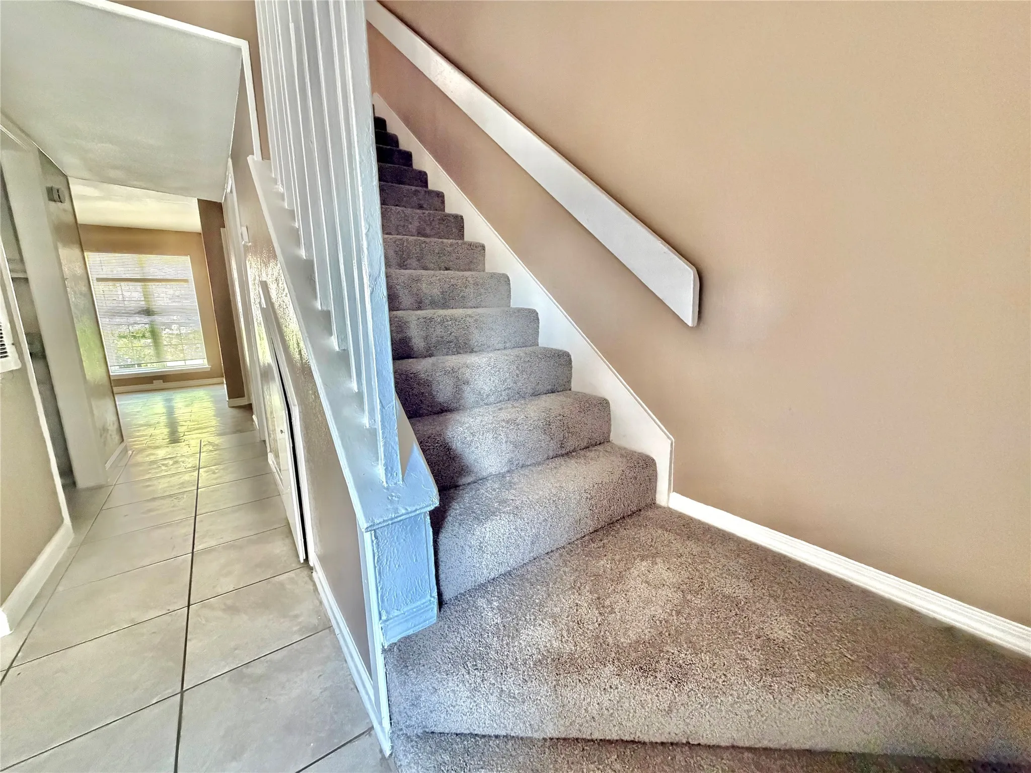 Carpeted staircase with white balustrade and handrail