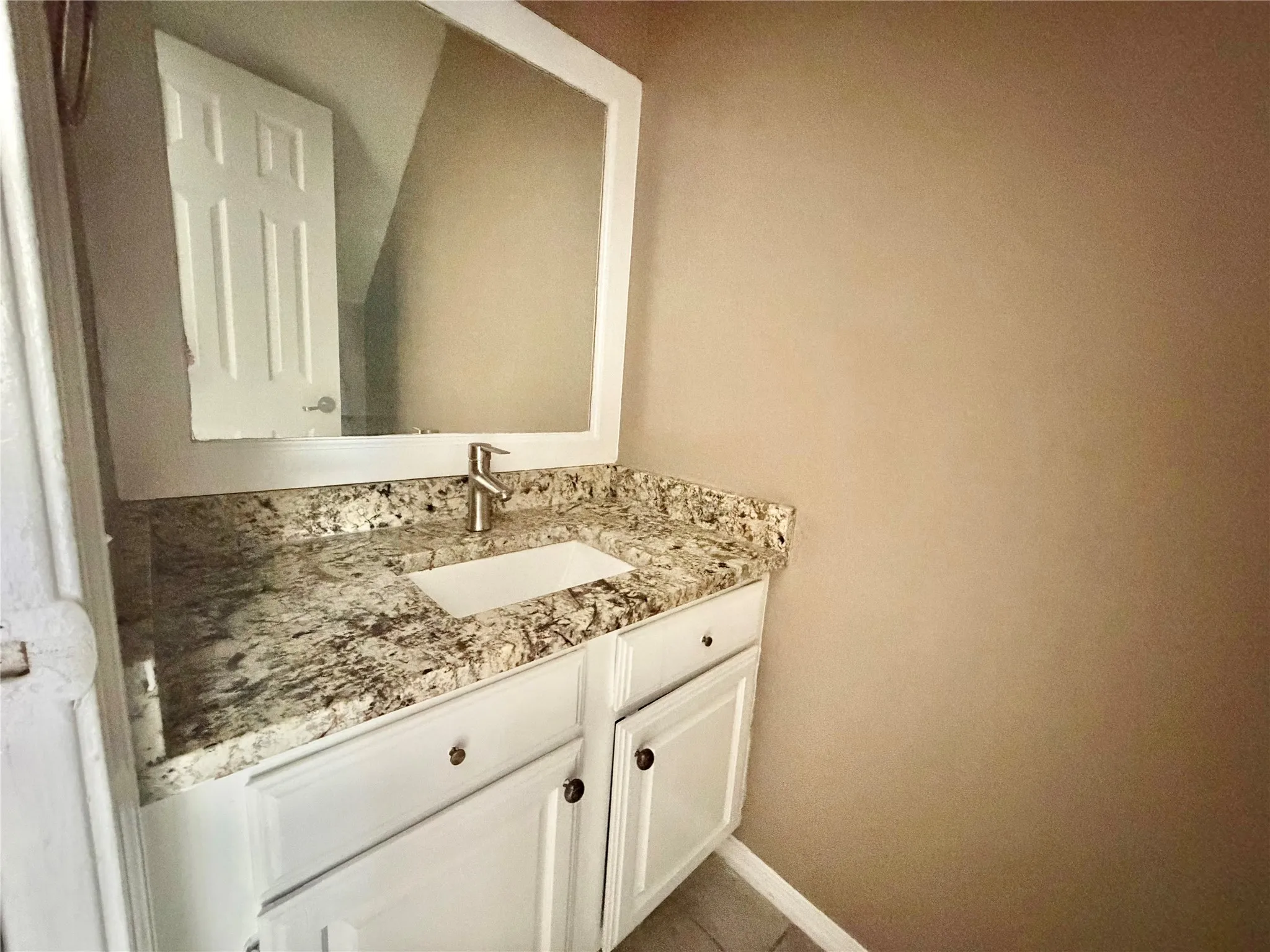 Bathroom vanity featuring a white cabinet, integrated sink, and granite countertop