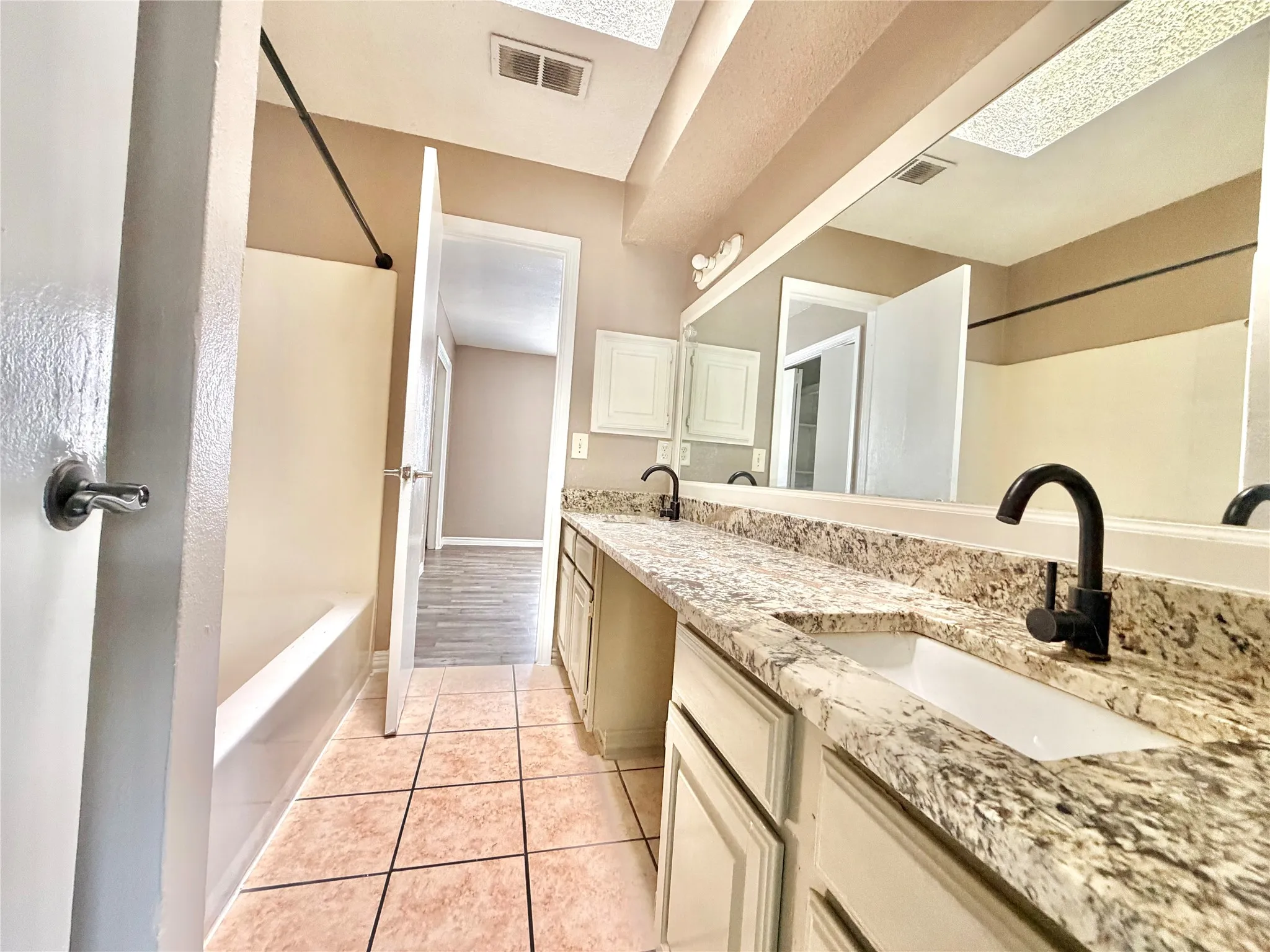 Bathroom featuring a double vanity with stone-finish countertops, undermount sinks, and matte black faucets