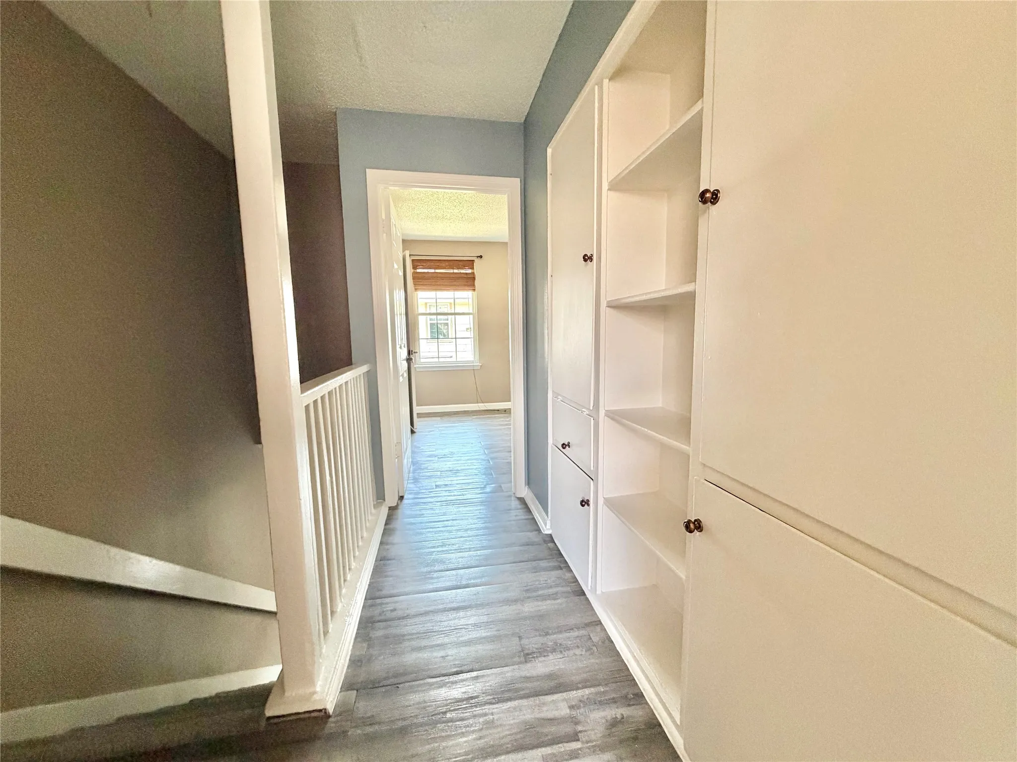 Hallway featuring integrated built-in cabinetry with both enclosed storage and open shelving