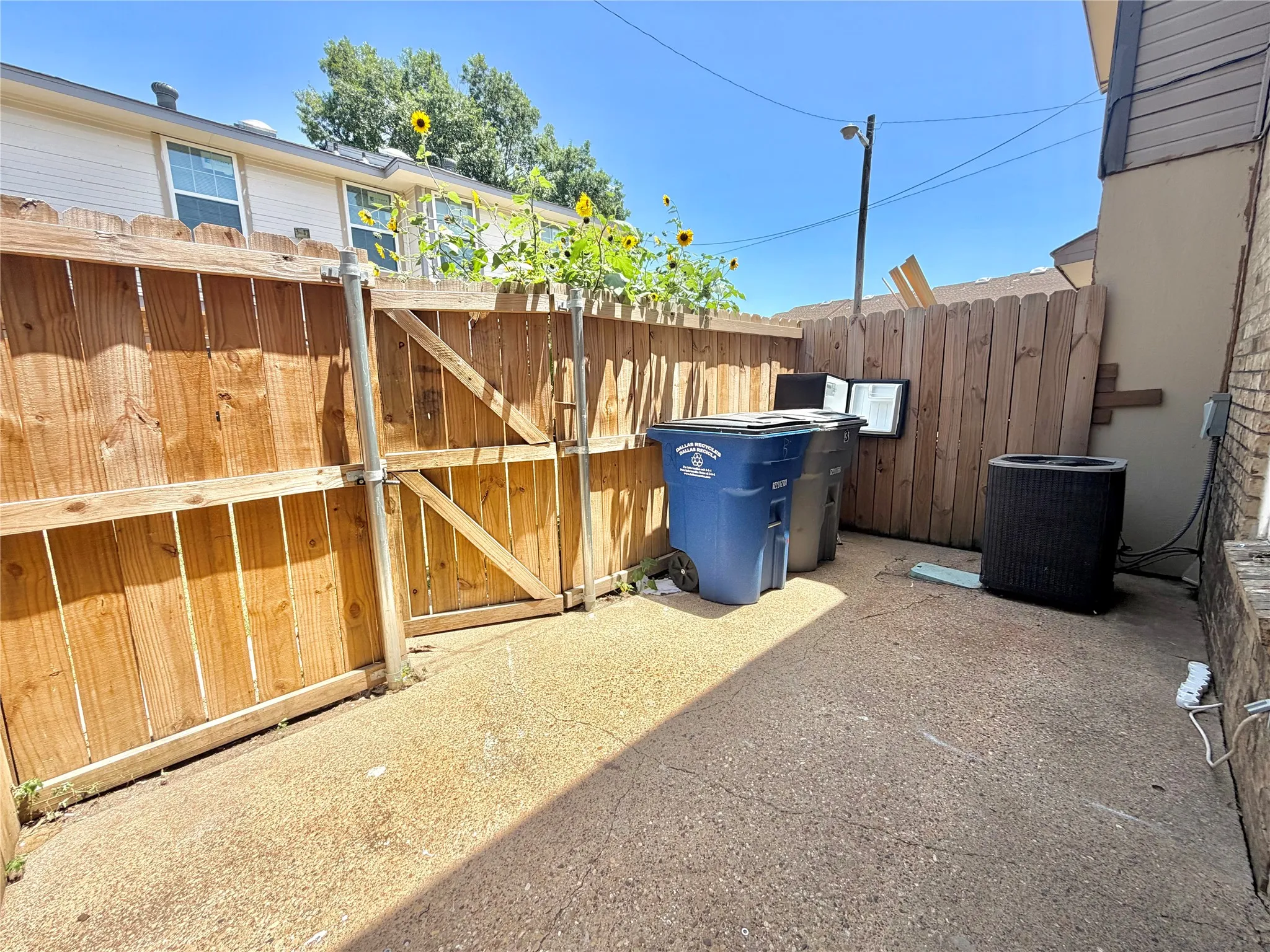Private outdoor space featuring a wood fence, concrete ground, and a small gate