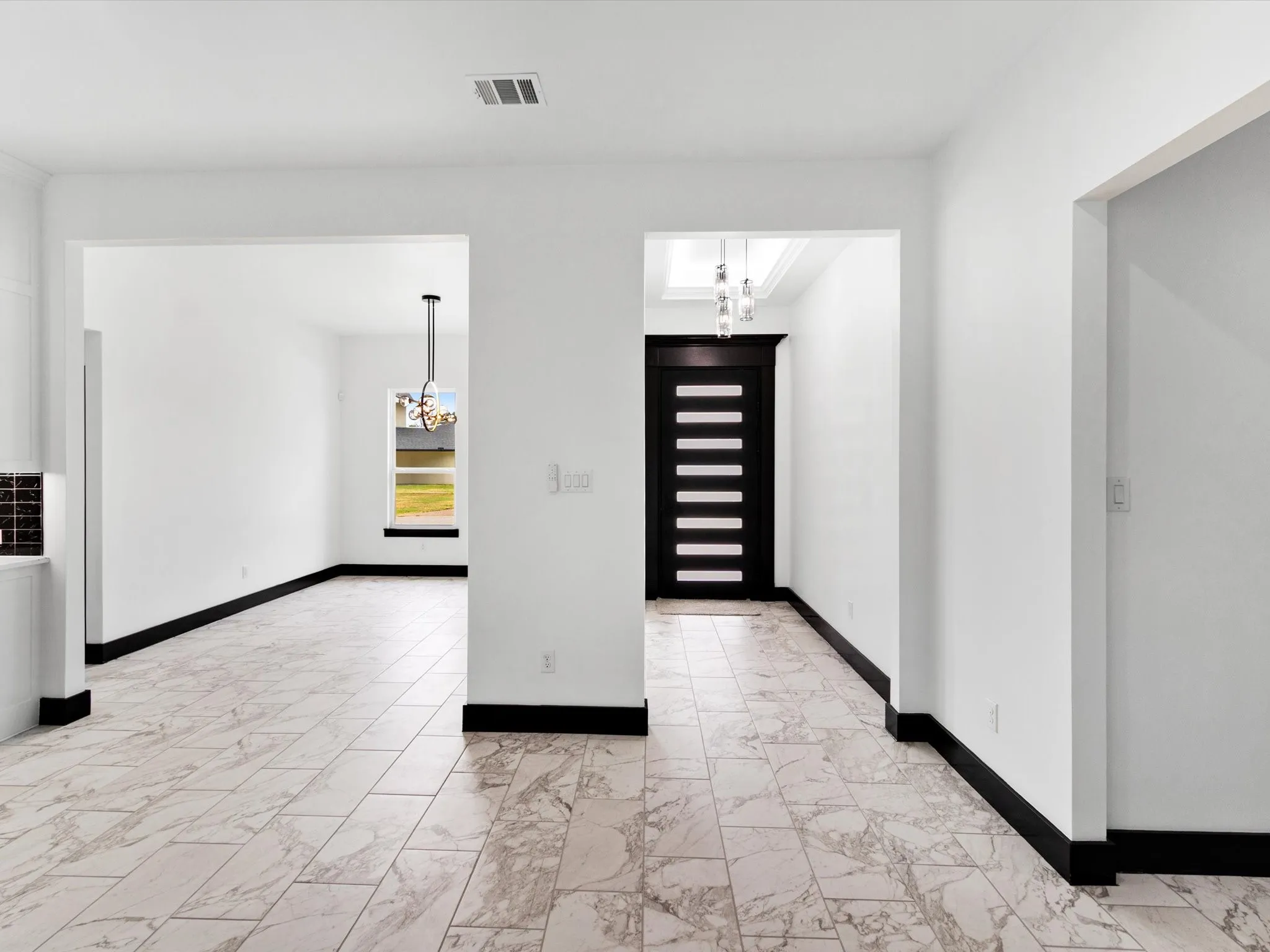 Spacious interior featuring patterned tile flooring and contrasting black baseboards