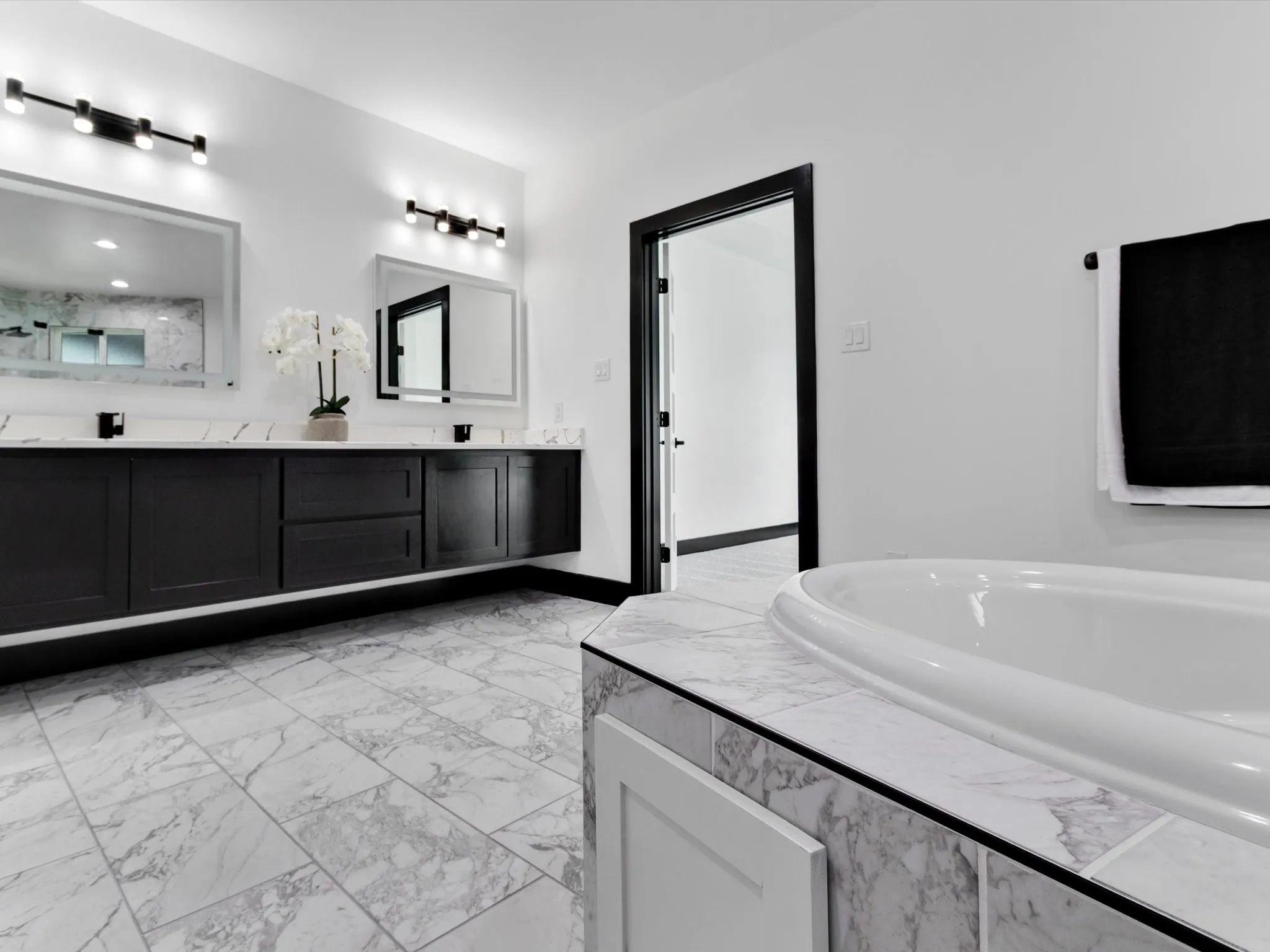 Bathroom featuring a dual vanity with dark cabinetry, white countertops, and dual mirrors