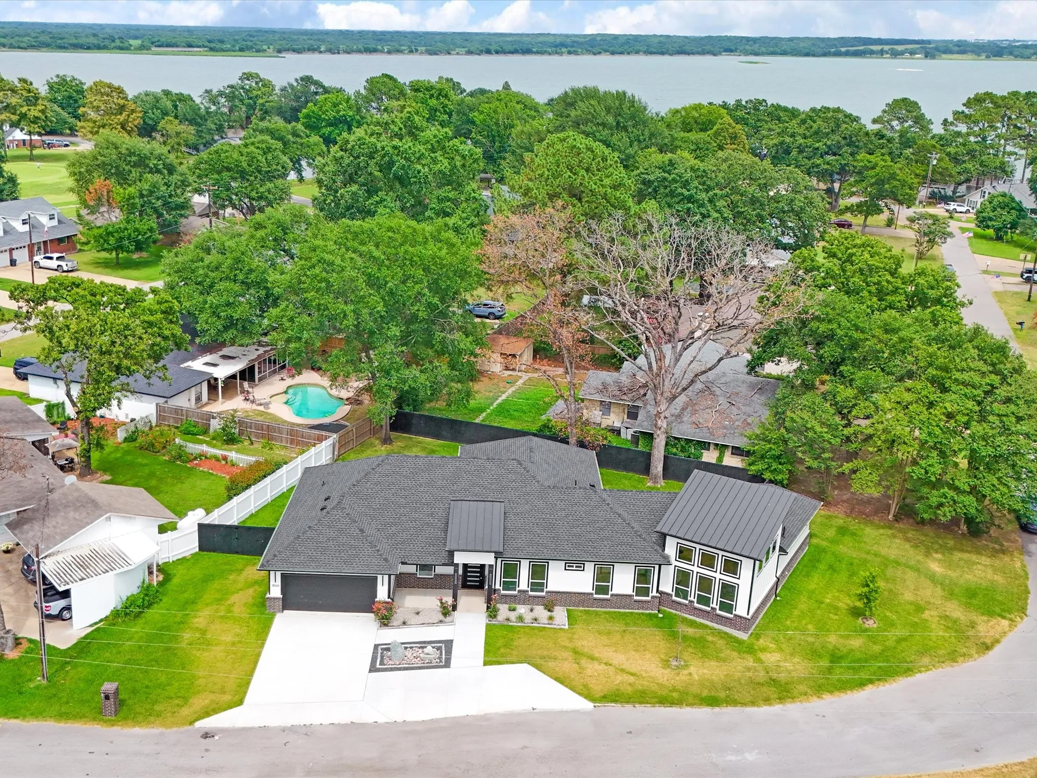 Contemporary residence featuring a dark shingle roof with metal accents, white siding, and black trim