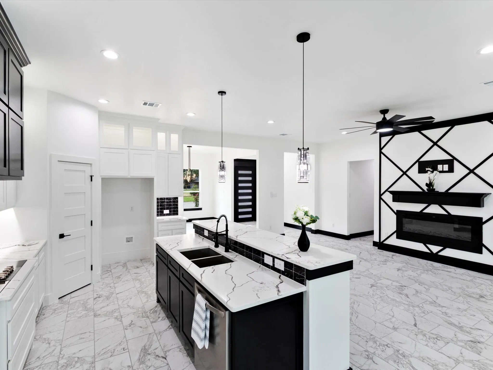 Open-concept living space featuring a kitchen island with dual sinks, pendant lighting, and marble-look tile flooring