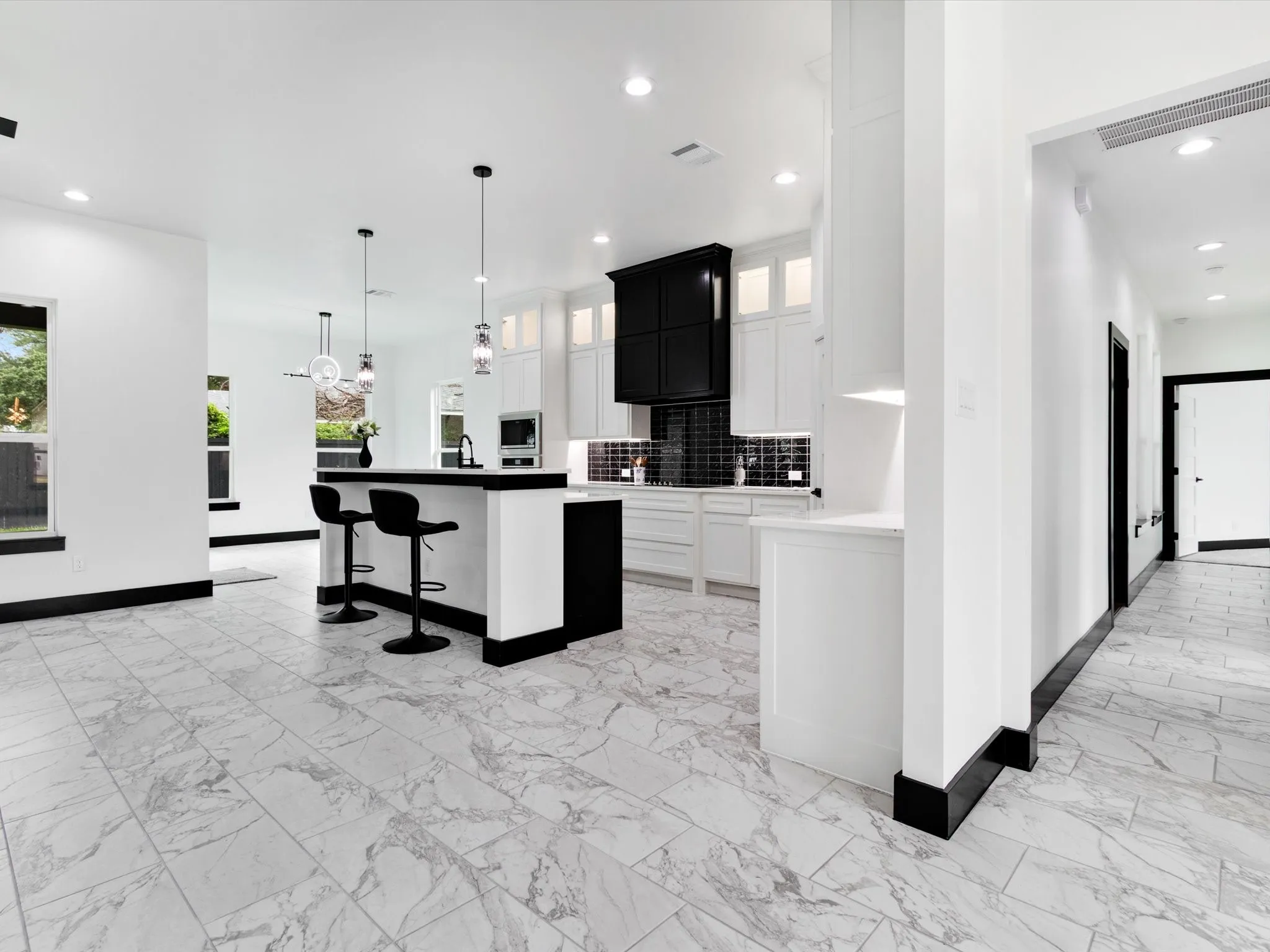Kitchen featuring white cabinetry, black vent hood, and dark subway tile backsplash