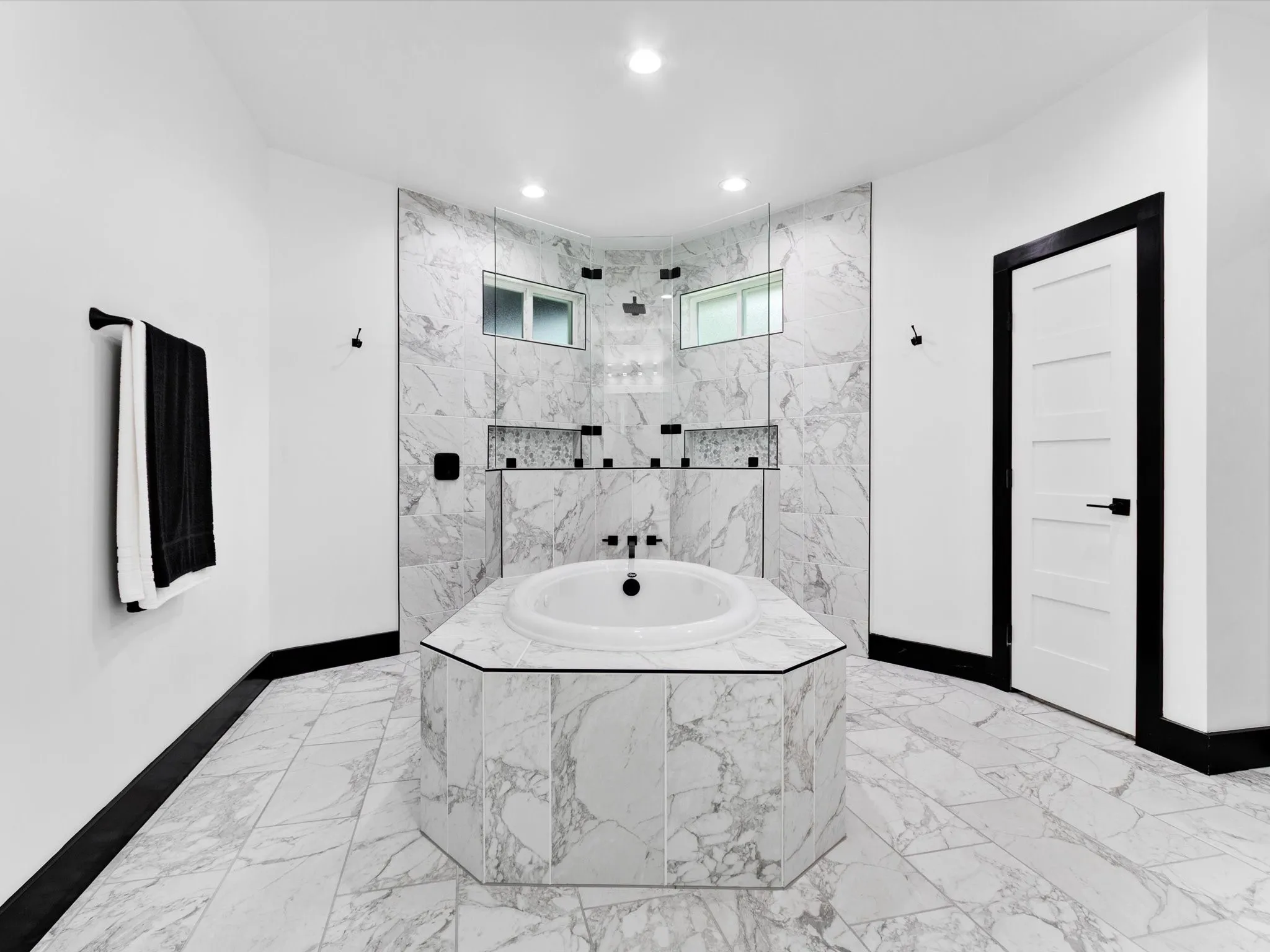 Luxurious bathroom featuring a built-in soaking tub, marble-style tile flooring, and a spacious walk-in shower with dual shower heads