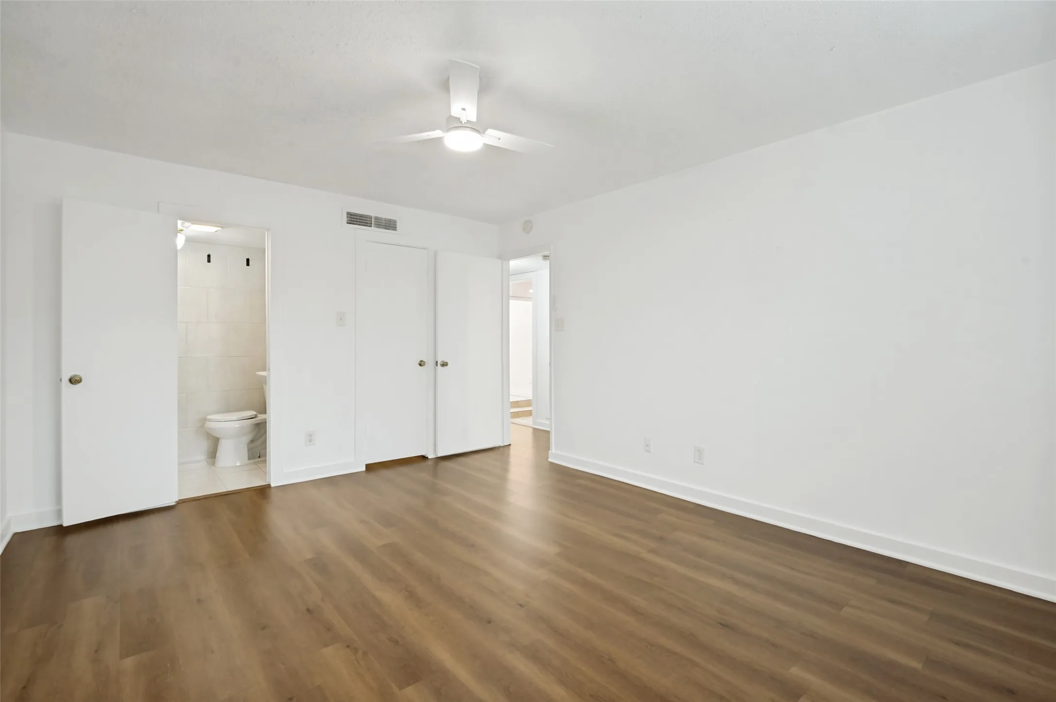 Spacious room with wood-finish flooring and a ceiling fan with integrated lighting