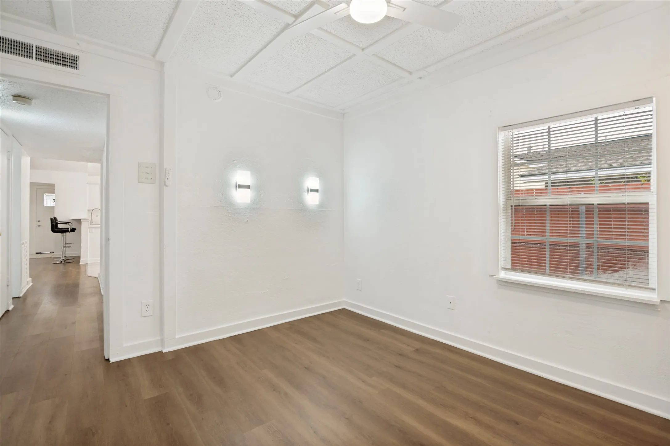 Room featuring wood-finish flooring, white baseboards, and a window with blinds