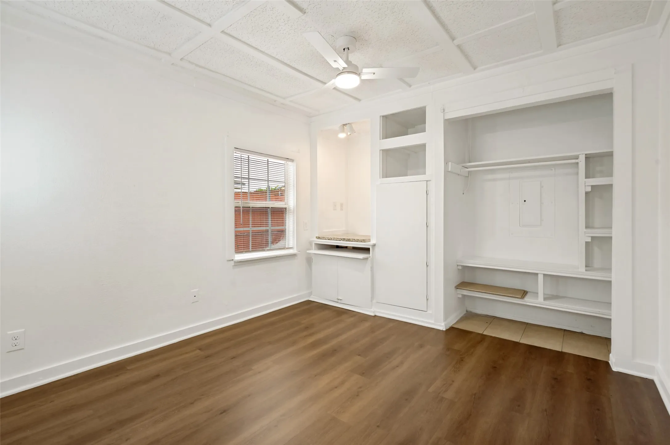Room featuring wood-finish flooring, a decorative ceiling, and built-in storage solutions
