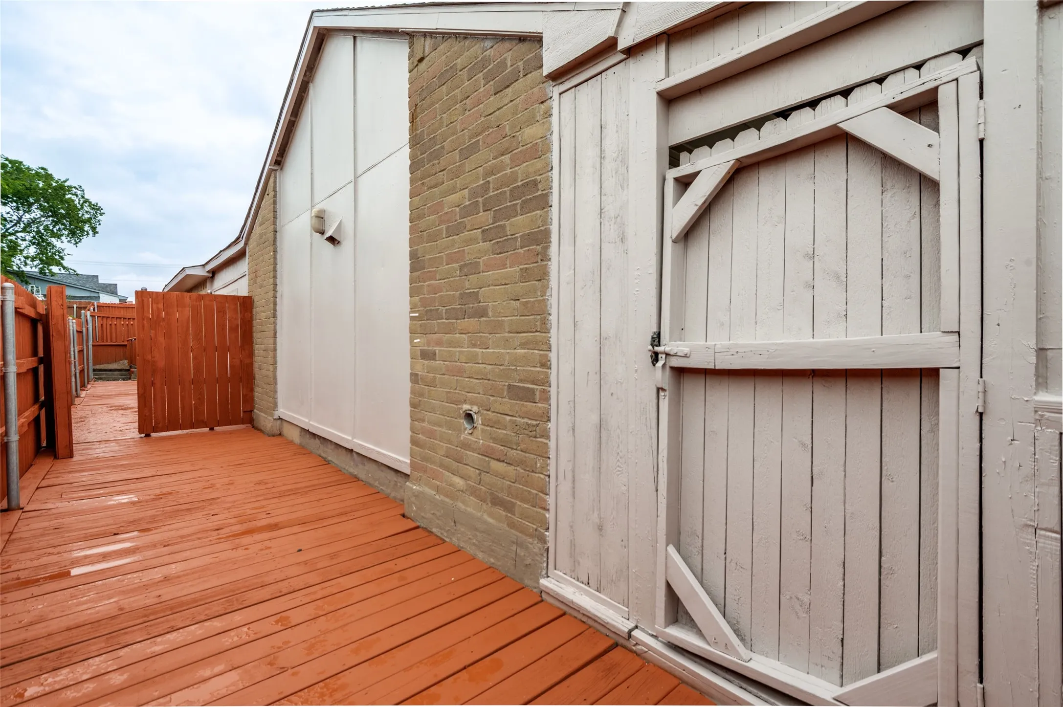 Expansive wood deck with a red stain finish, featuring a light-colored wood gate and a privacy fence