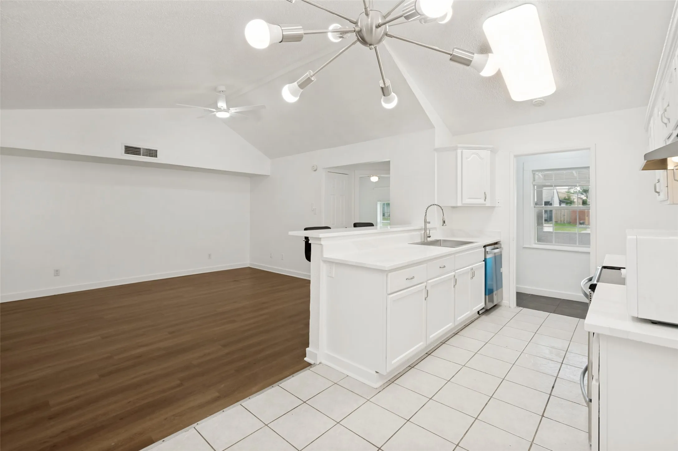 Open-concept kitchen featuring white cabinetry, light countertops, and a stainless steel sink