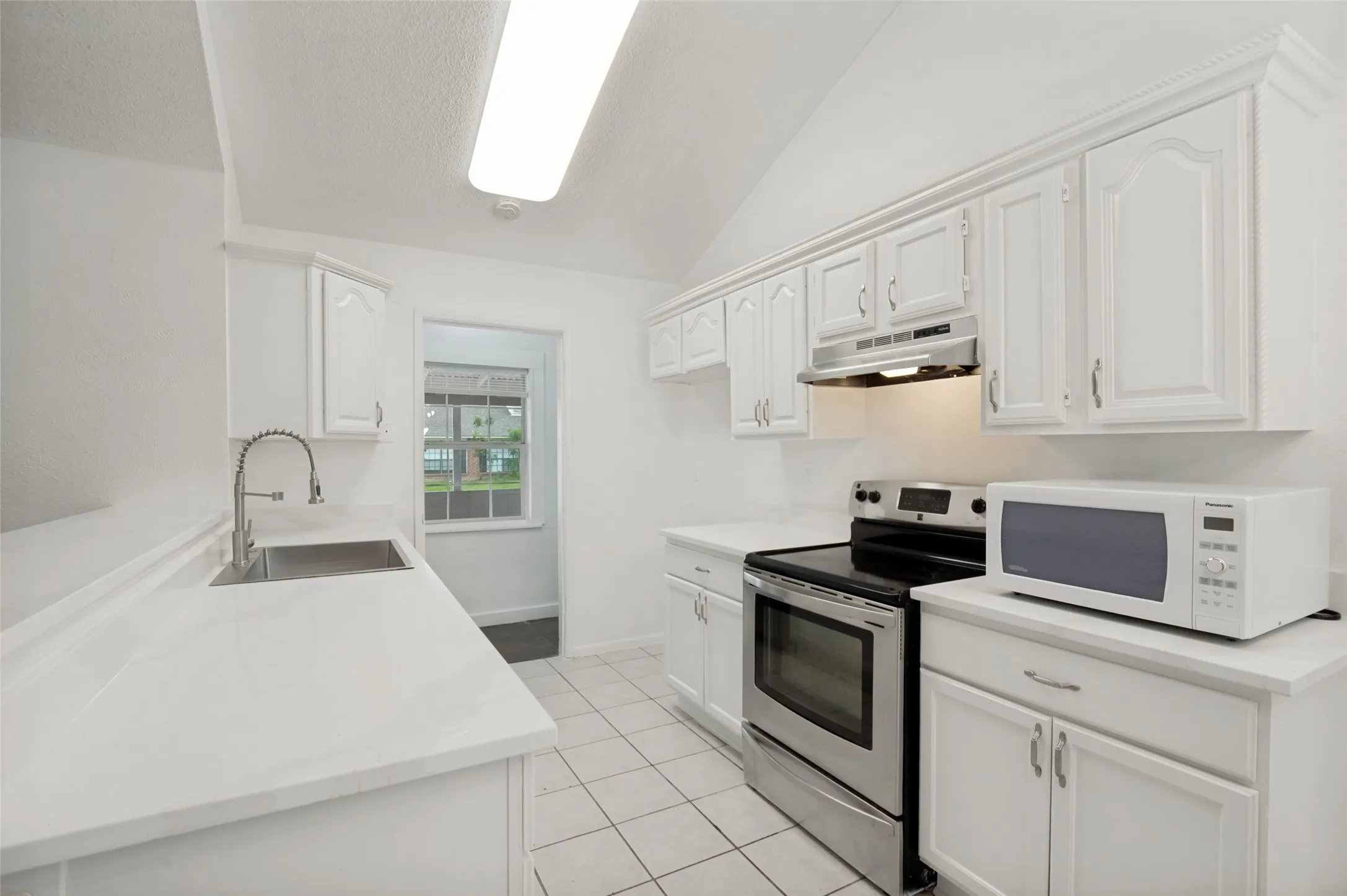 Kitchen featuring white cabinetry, white countertops, stainless steel sink with a pull-down faucet, and a stainless steel oven/range