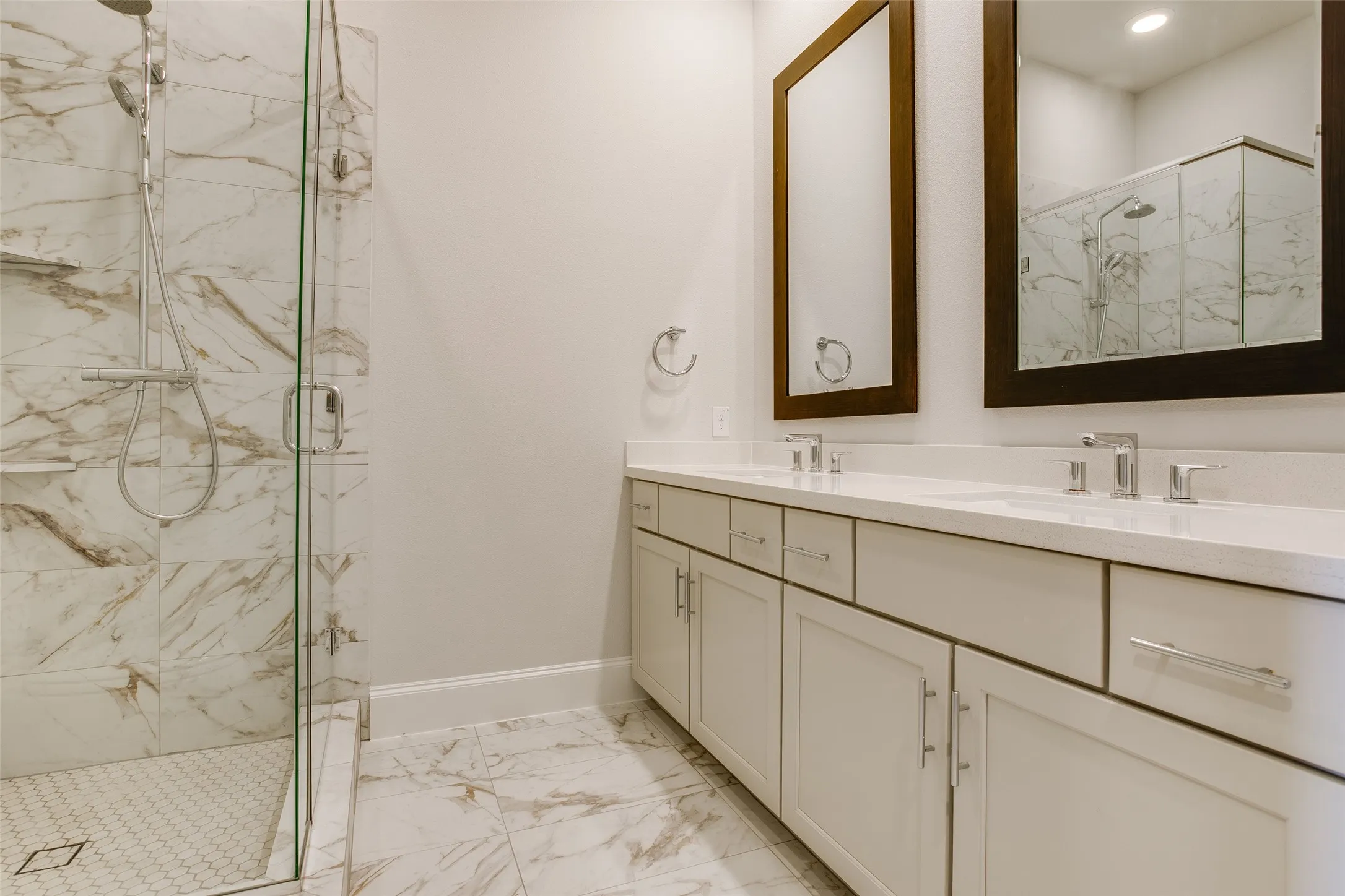 Spacious bathroom featuring a dual vanity with white cabinetry, light-toned countertop, and polished chrome fixtures