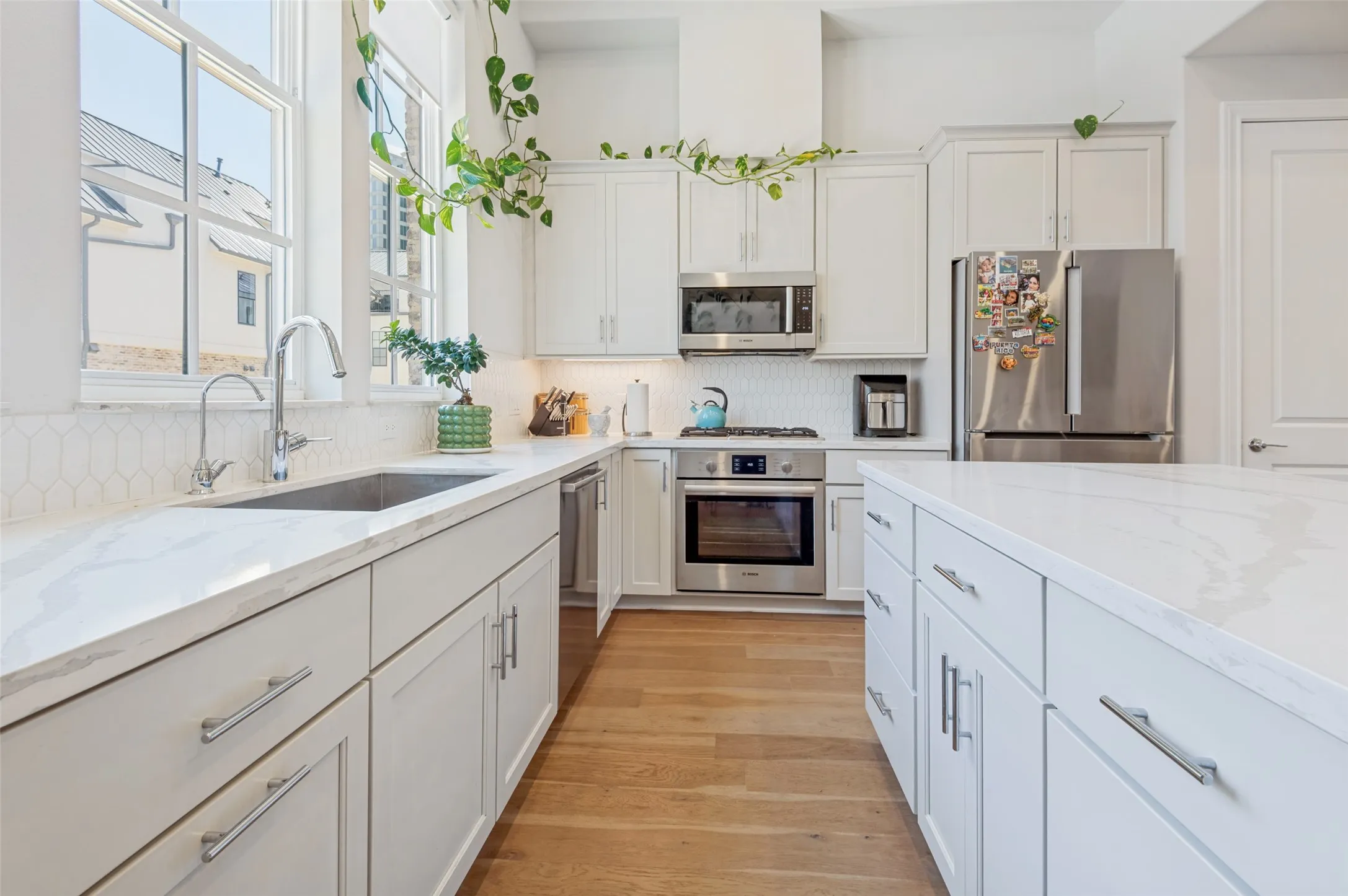 Contemporary kitchen featuring white cabinetry, light countertops, stainless steel appliances, a center island, and wood-finish flooring