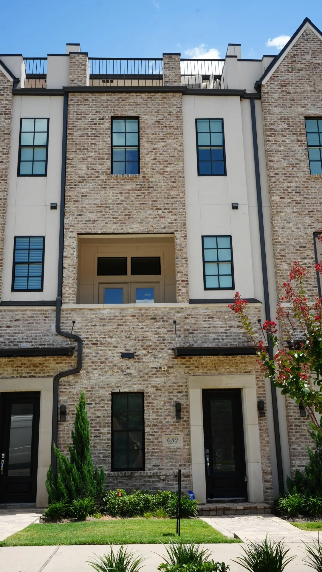 Multi-story townhome exterior featuring light-toned brick and stucco facade