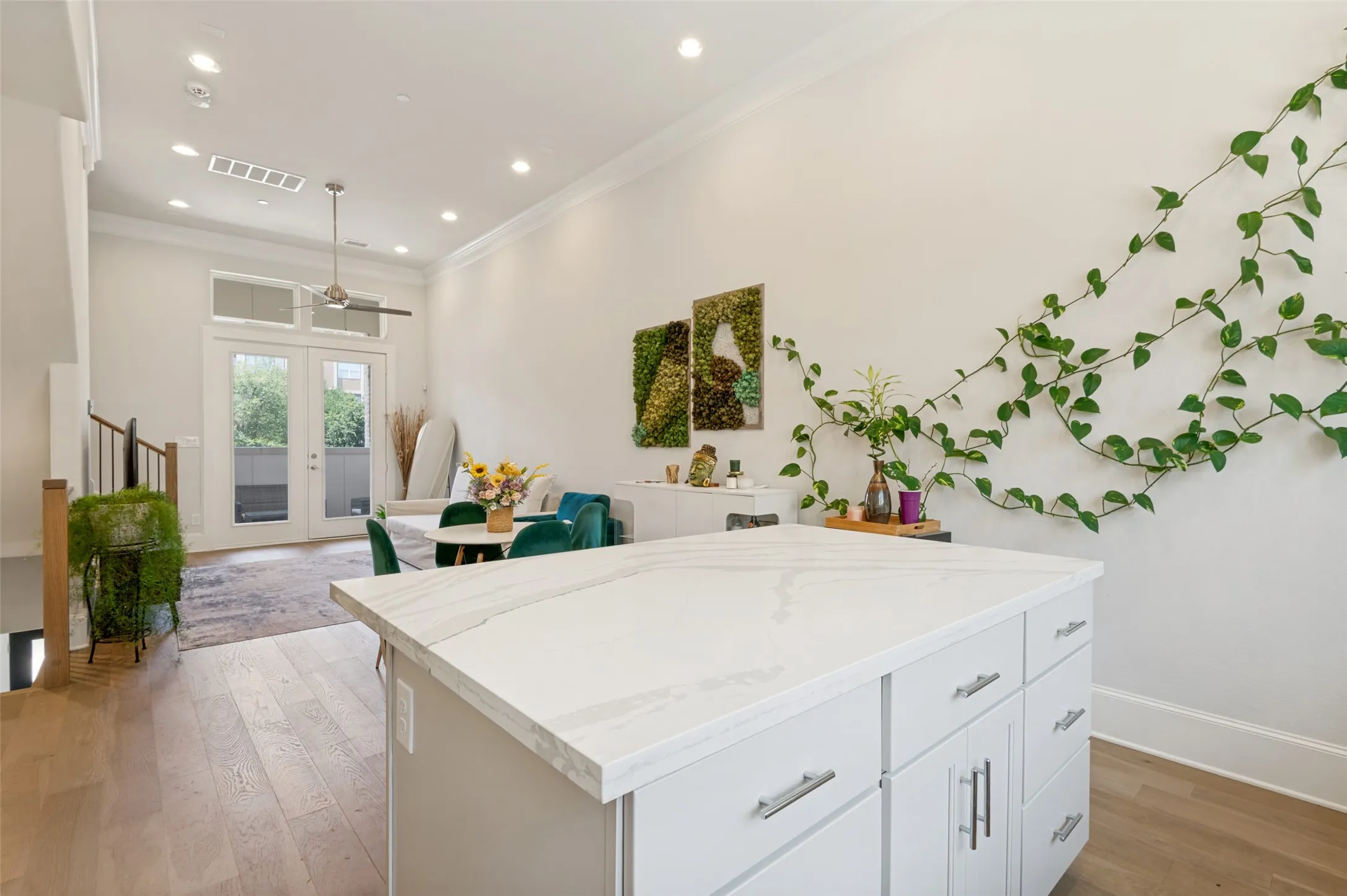 Kitchen island featuring a white countertop with subtle veining, light wood-finish flooring, recessed lighting, double French doors, and high ceilings