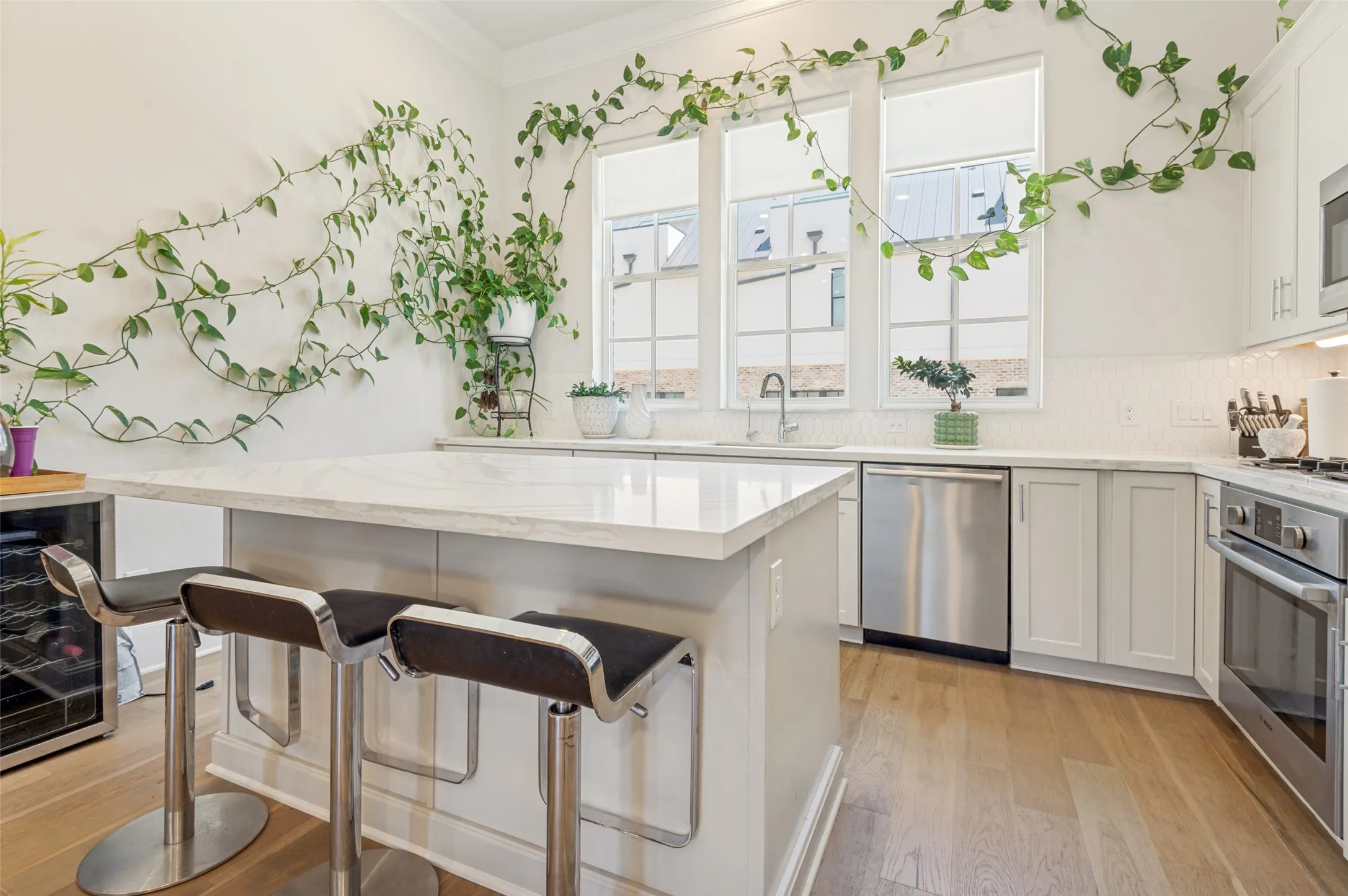 Kitchen featuring a large central island with a light-toned countertop, stainless steel appliances, light wood-finish flooring, and multiple large windows