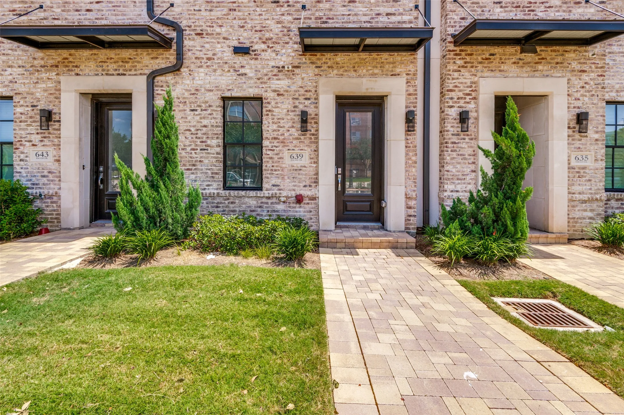 Brick facade featuring black framed windows and doors with stone surrounds