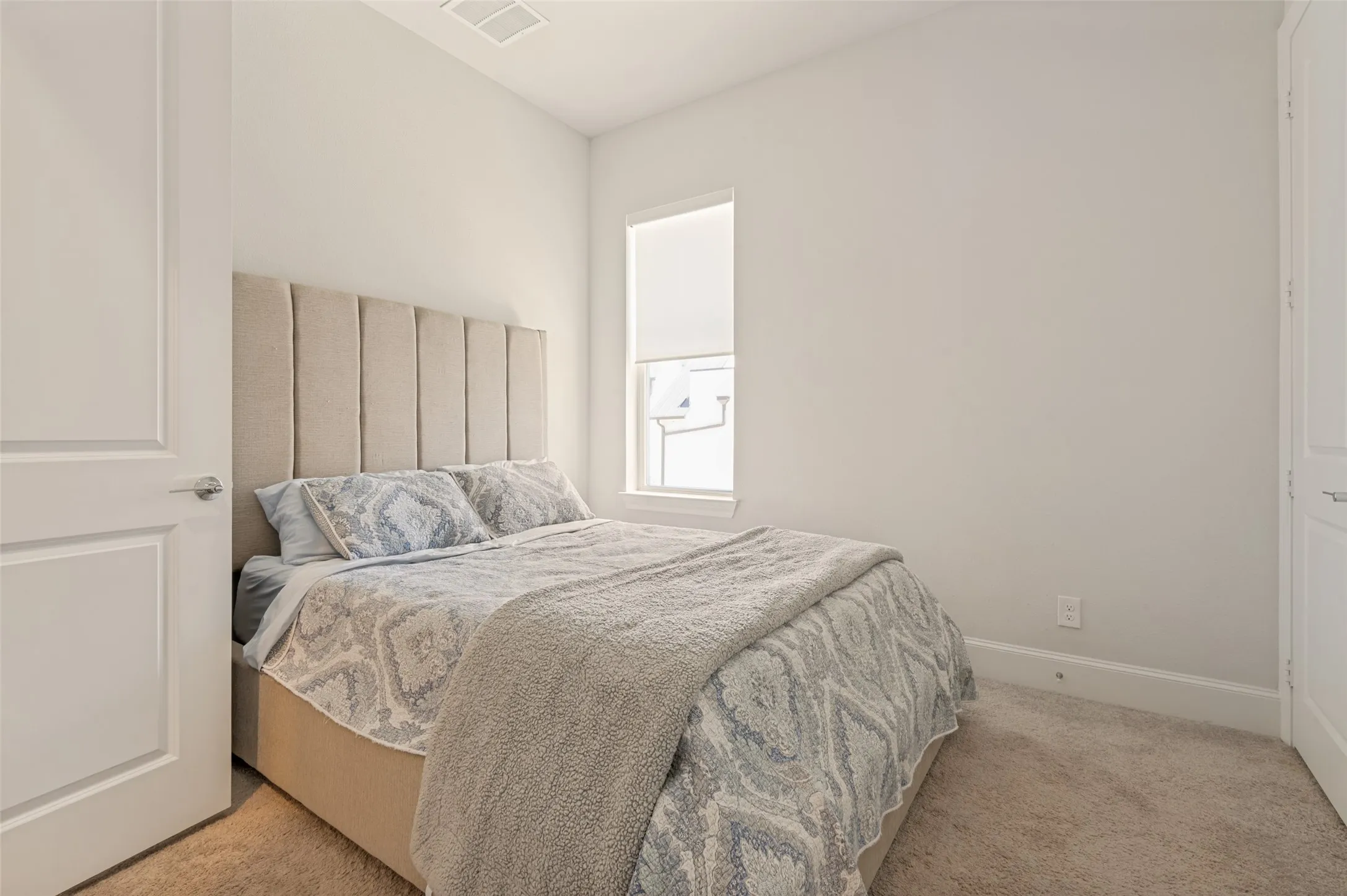 Carpeted bedroom with a window, white walls, and white trim