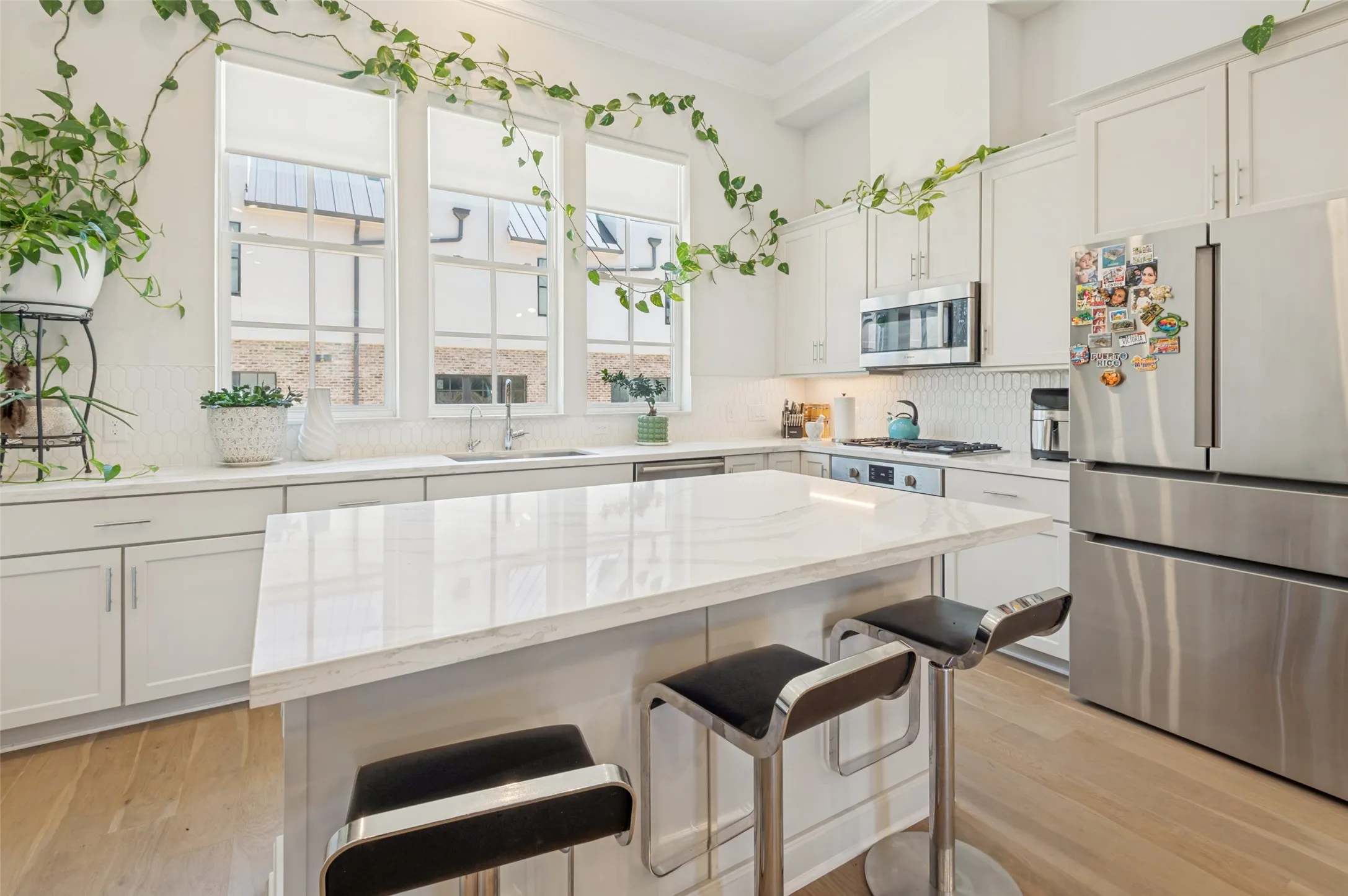 Contemporary kitchen featuring light wood-finish flooring and an expansive central island with a light-toned countertop