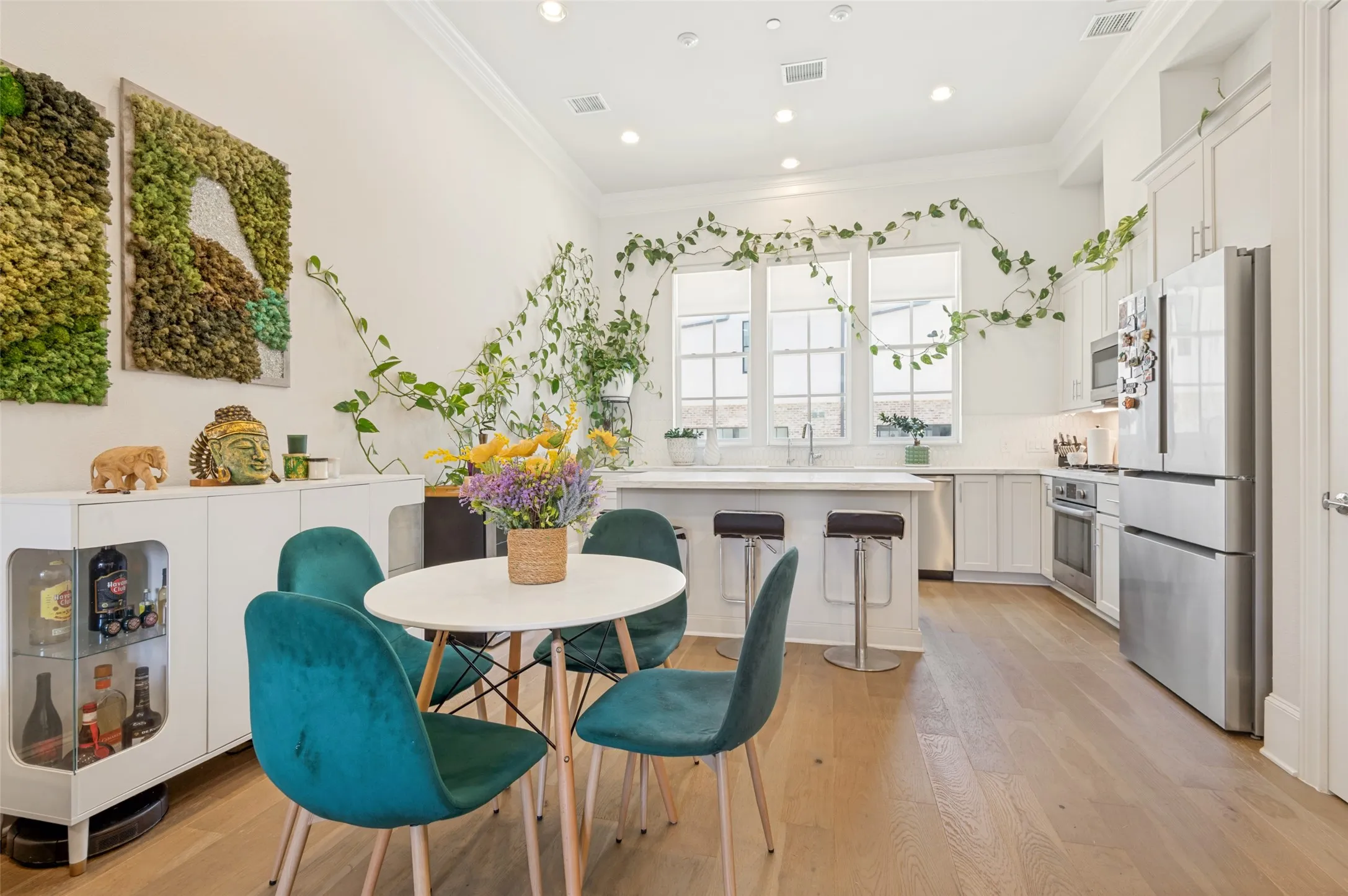 Open-concept kitchen and dining area featuring light wood-finish flooring, white cabinetry, stainless steel appliances, a kitchen island with seating, and recessed lighting