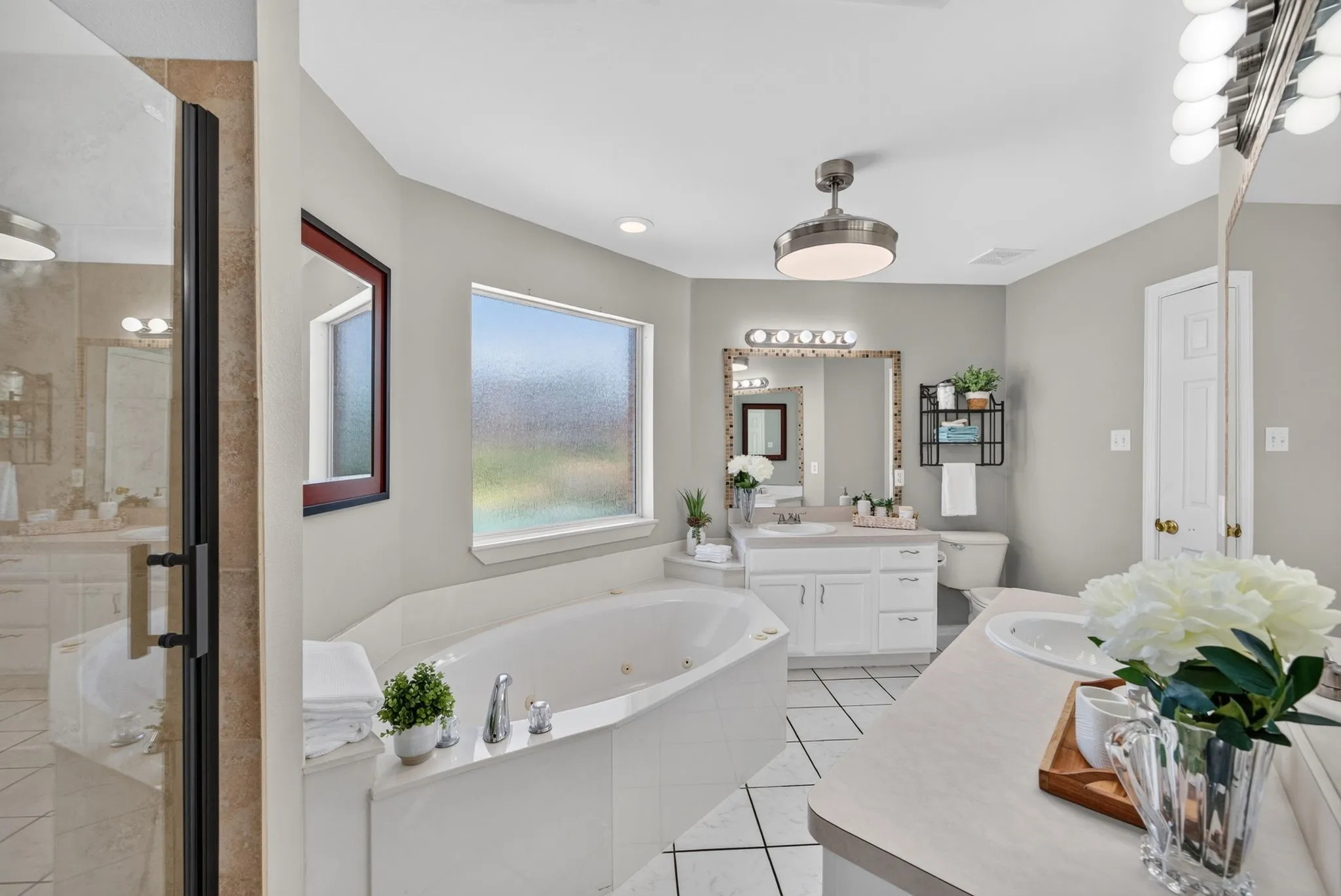 Soaking tub with white surround, frosted window, and tile flooring