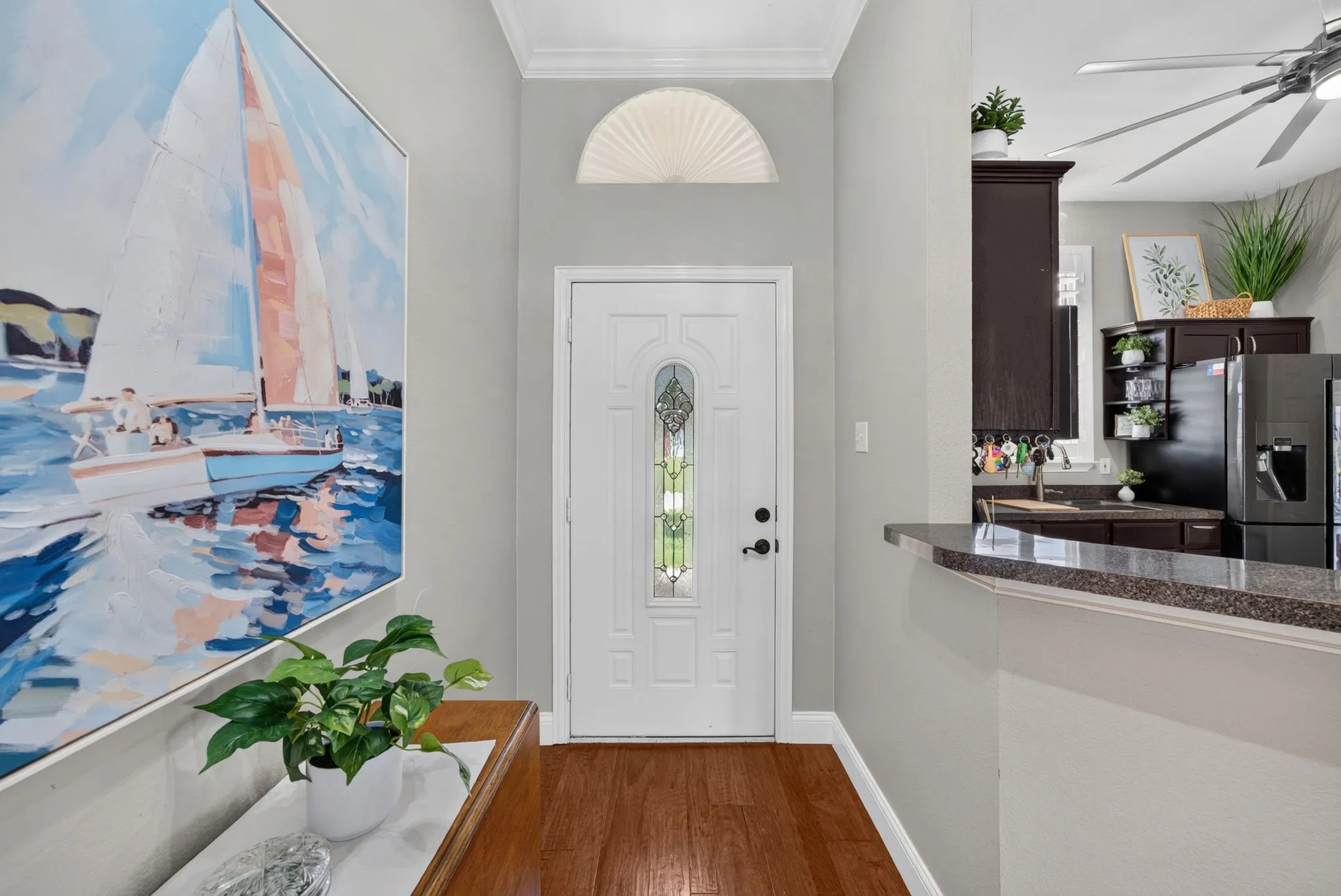 Entryway featuring a white paneled door with decorative glass inserts, an arched transom window, and wood-finish flooring