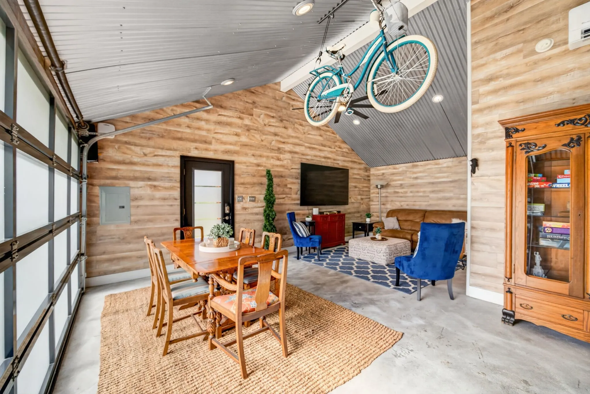Open-concept living space featuring wood-finish wall panels and a corrugated metal ceiling with recessed lighting