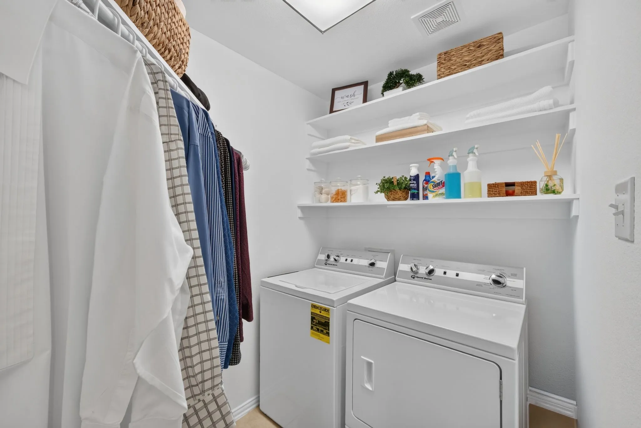 Dedicated laundry area featuring a white washing machine and dryer, built-in shelving, a clothes hanging rod, and light wood-finish flooring