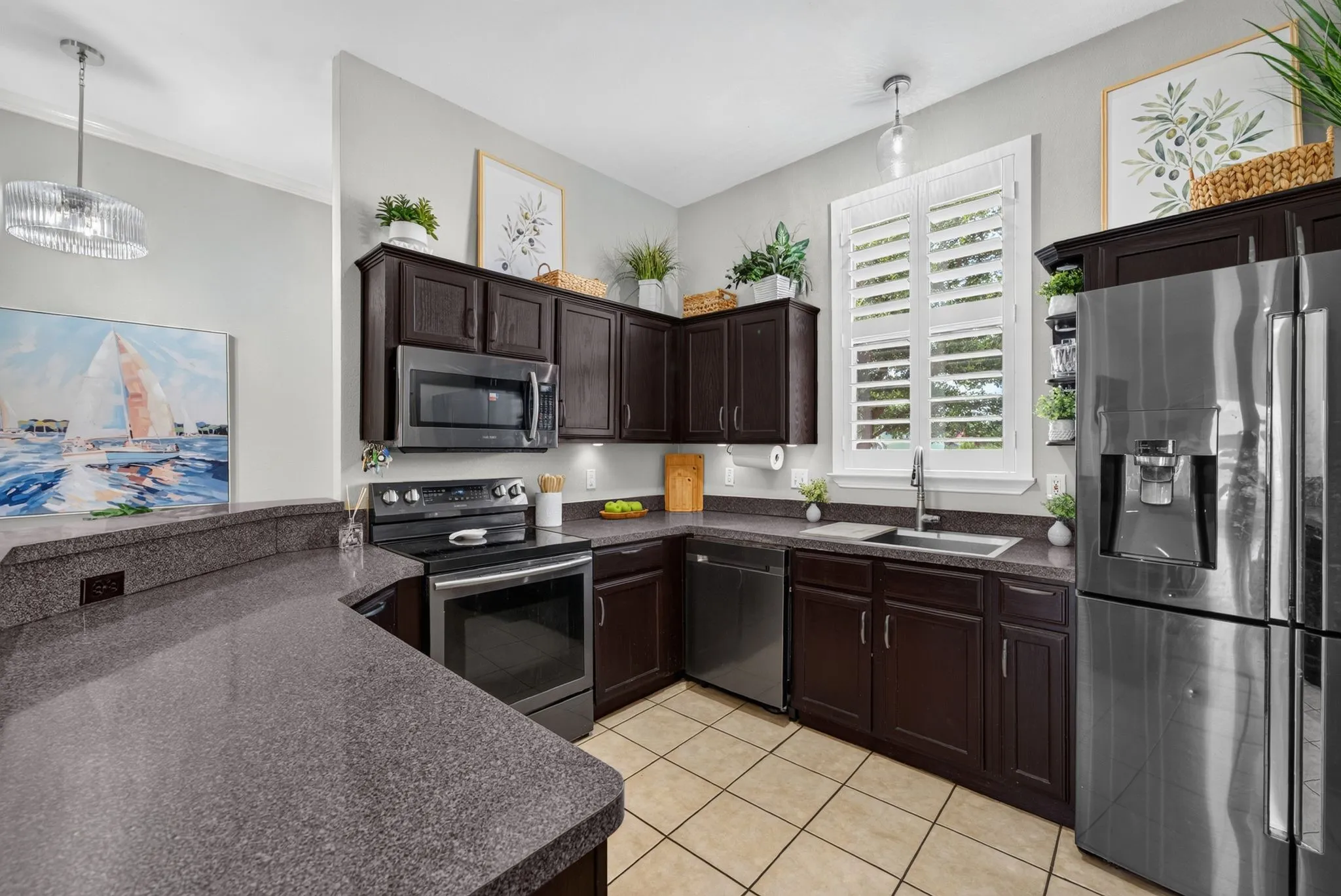 Kitchen featuring dark wood cabinetry, stainless steel appliances, speckled countertops, and a double basin sink